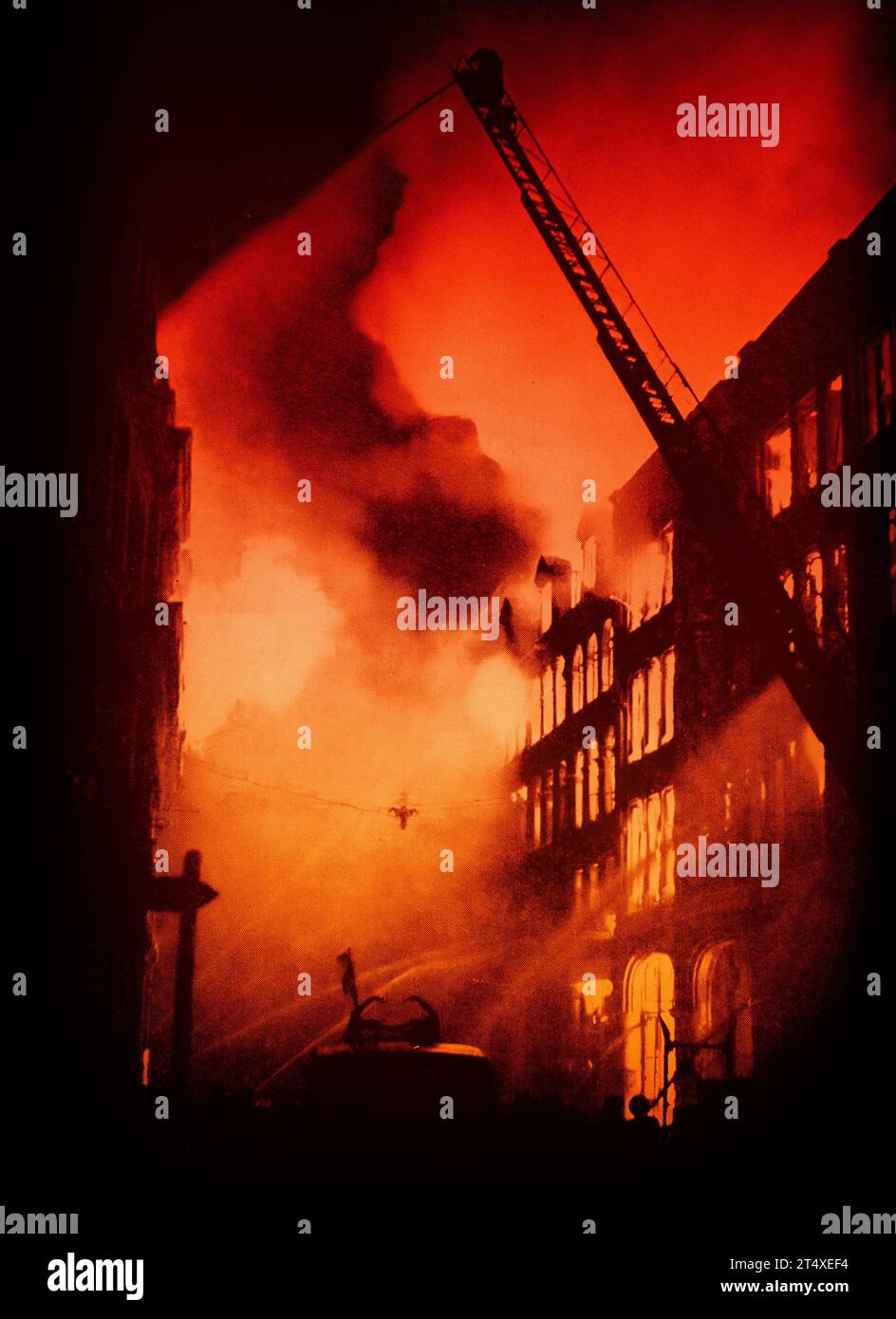 Shortly after midnight on the 21st August 1940, the first bombs were dropped by the Luftwaffe on London, England, causing a fire in a large commercial building.   Originally in black and white the colour has been recently added. Stock Photo
