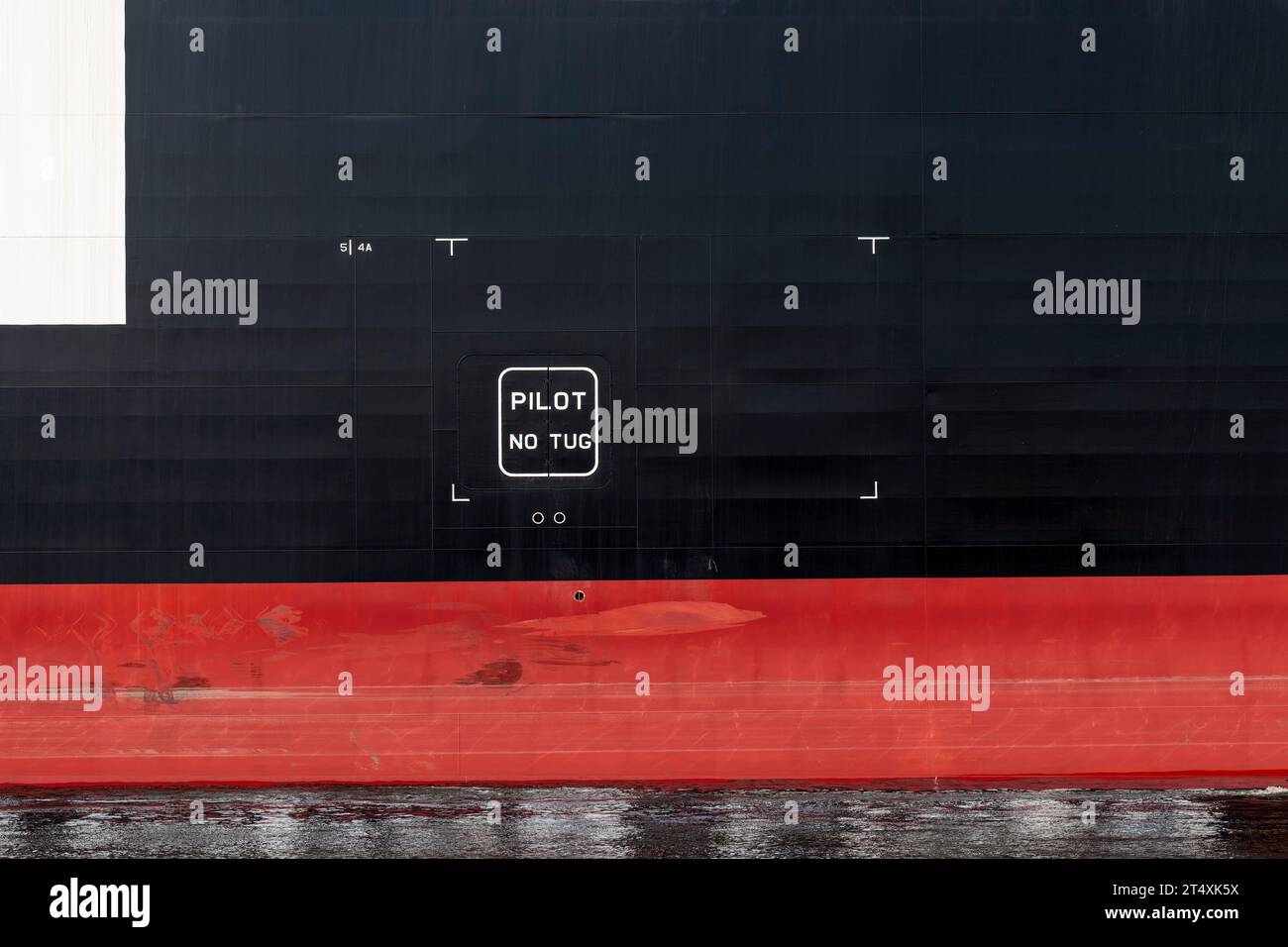 Section of the black and red hull of a ship with letters PILOT No Tug