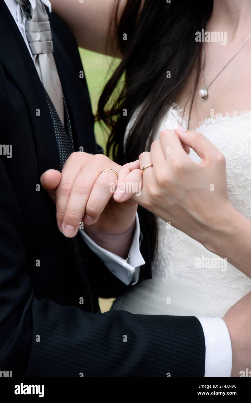 Newlywed couple's hands with pinkies intertwined and wedding rings