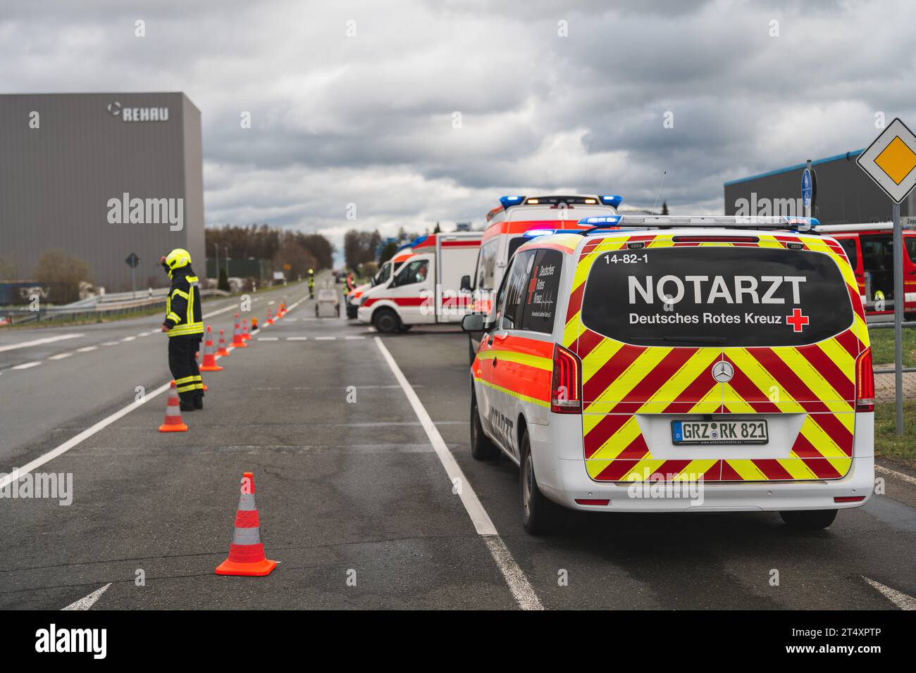 Ein Notarzteinsatzfahrzeug steht auf einer Straßenkreuzung bei einem Verkehrsunfall.  Ein Feuerwehrmann sichert die Einsatzstelle ab.  Am 25.03.2023 Stock Photo