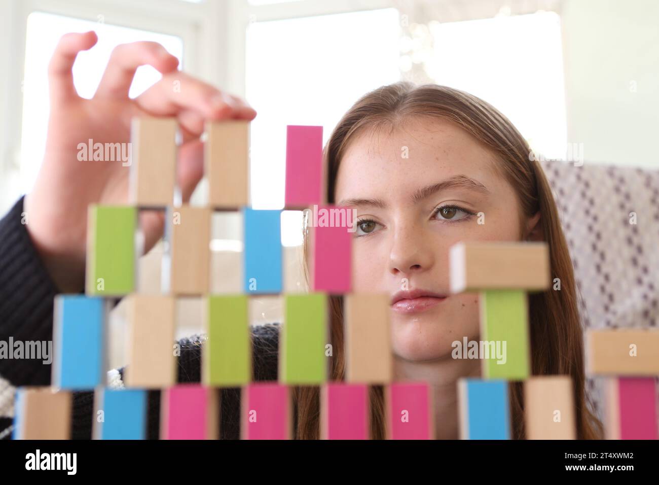 Teenage girl constructing a wall of wooden blocks and building a tower ...