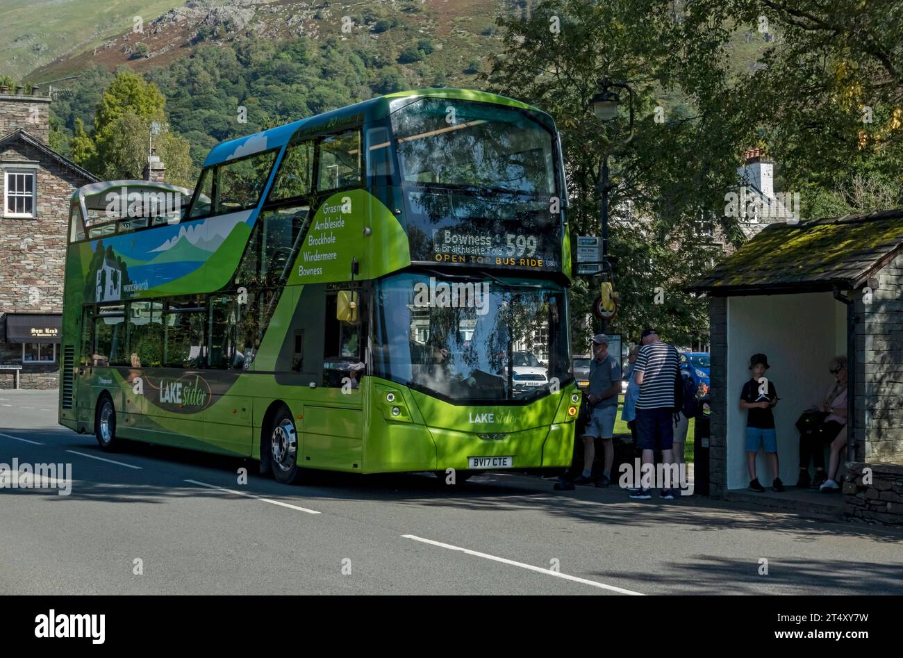 Open top bus sightseeing waiting at the village bus stop in summer Grasmere  Cumbria England UK United Kingdom GB Great Britain Stock Photo