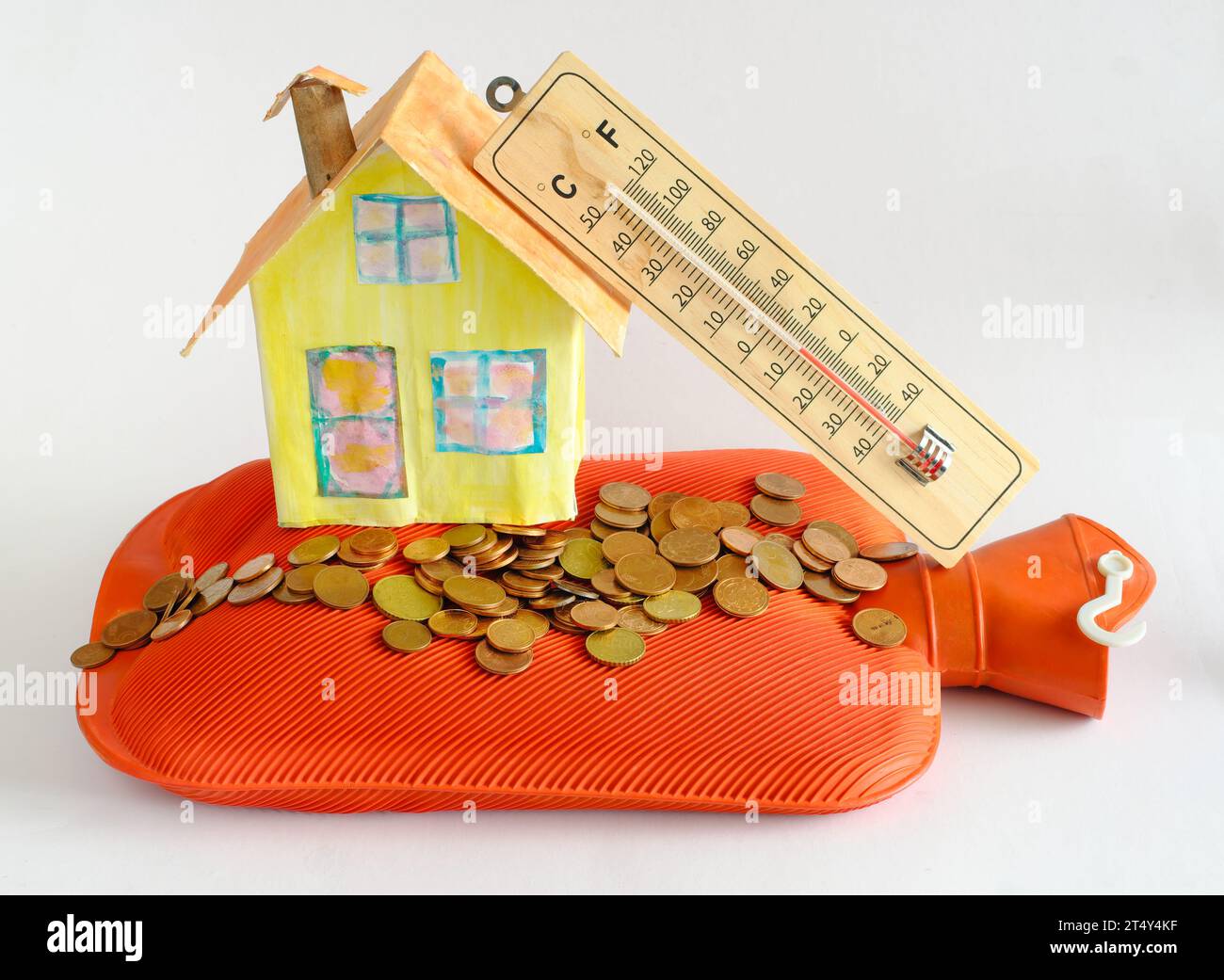 Model home with hot-water bottle, stacks of money and thermometer.Rising heating costs, Thermal insulation and energy prices due to shortage of heatin Stock Photo