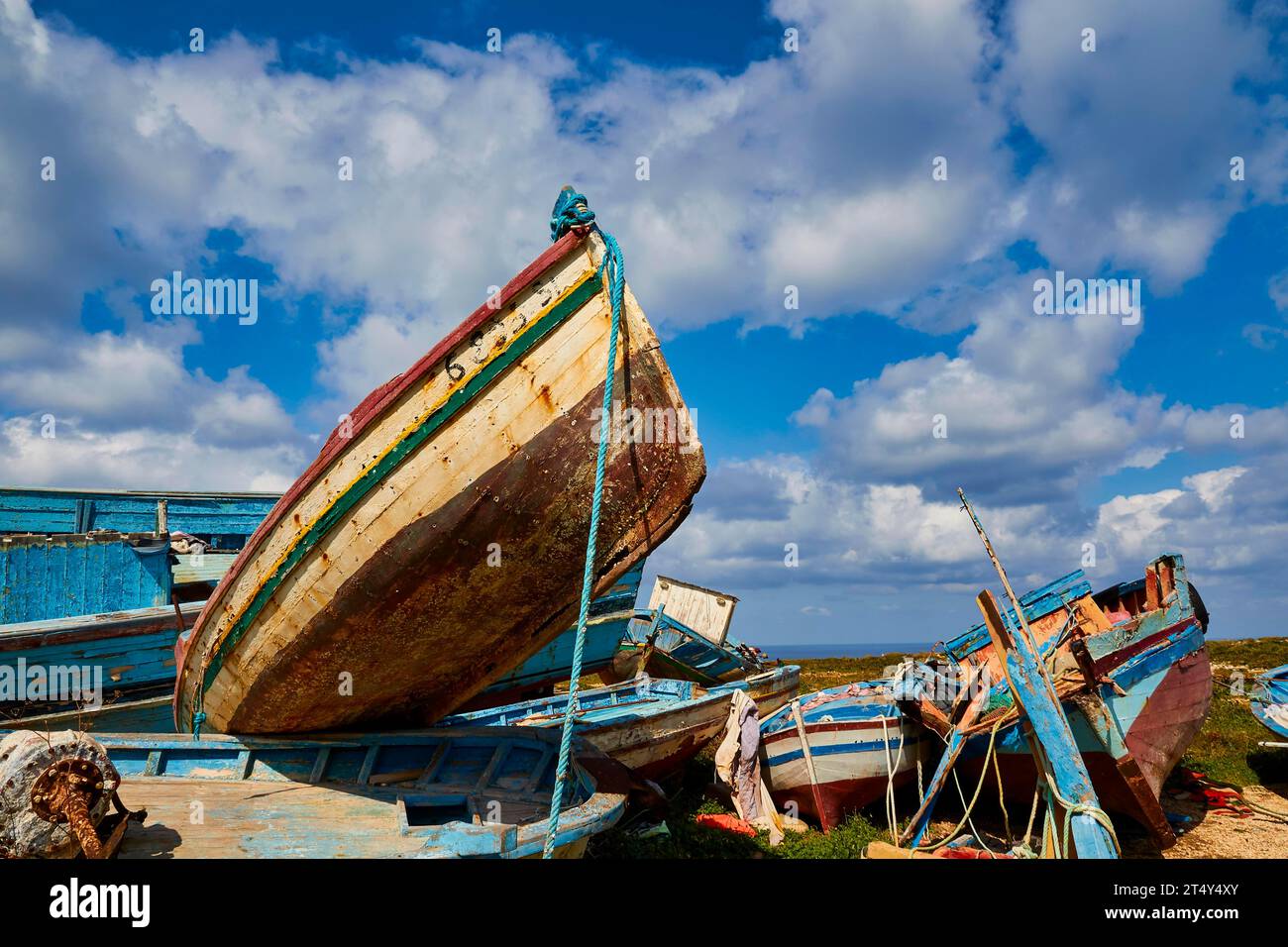 Boat reaching into the sky, refugee boats, Cimitero delle barche, boat graveyard, boat wrecks, blue cloudy dramatic sky, Lampedusa Island, Agrigento Stock Photo