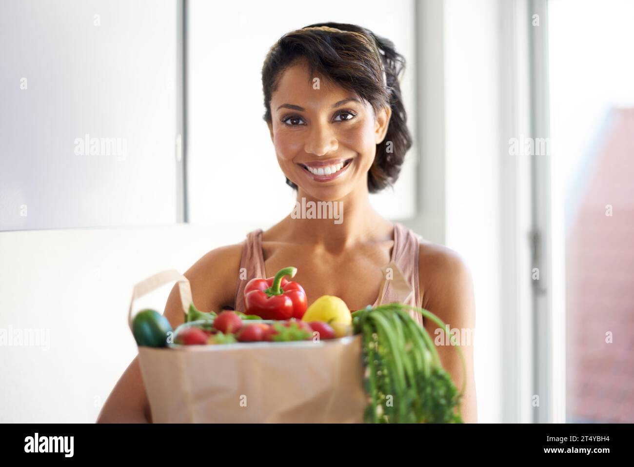 Happy woman, portrait and shopping bag in kitchen with groceries, vegetables or fresh produce at home. Female person, shopper or vegan smile with food Stock Photo