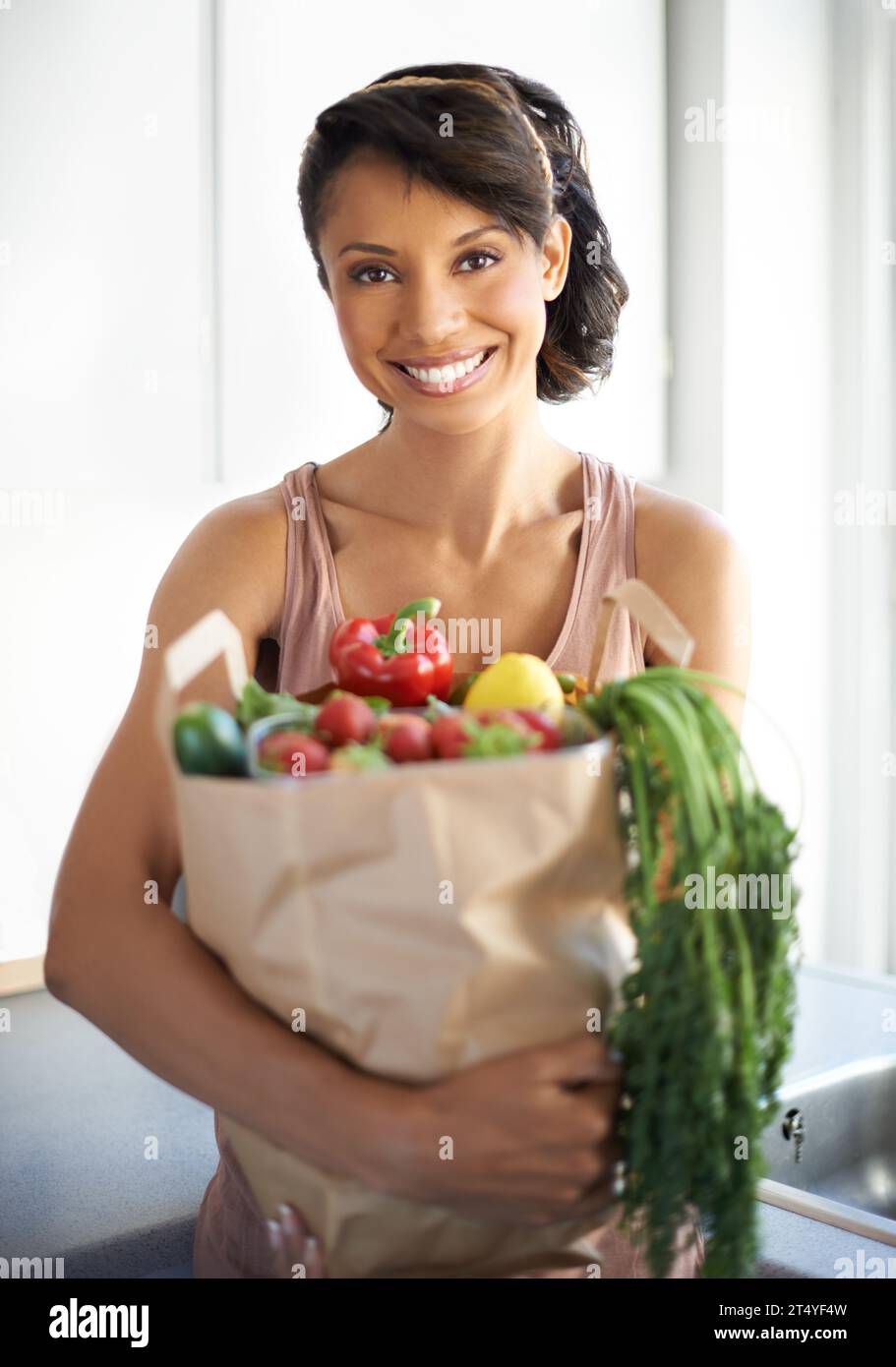 Happy woman, portrait and shopping bag with groceries, vegetables or fresh produce in kitchen at home. Female person, shopper or vegan smile with food Stock Photo