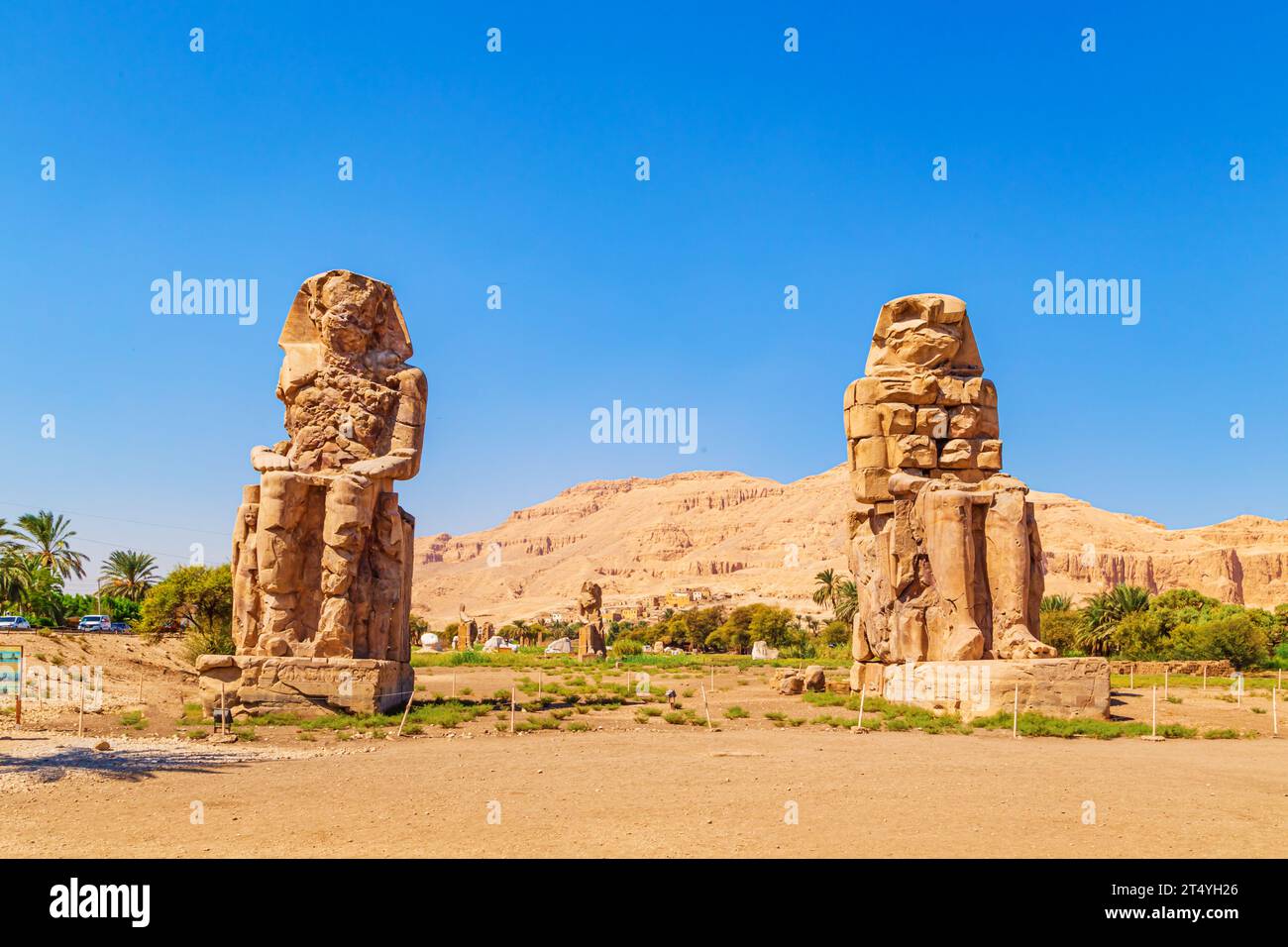 Famous  Colossi of Memnon - massive ruined statues of the Pharaoh Amenhotep III. Travel and tourist landmarks. Luxor, Egypt - October 21, 2023. Stock Photo
