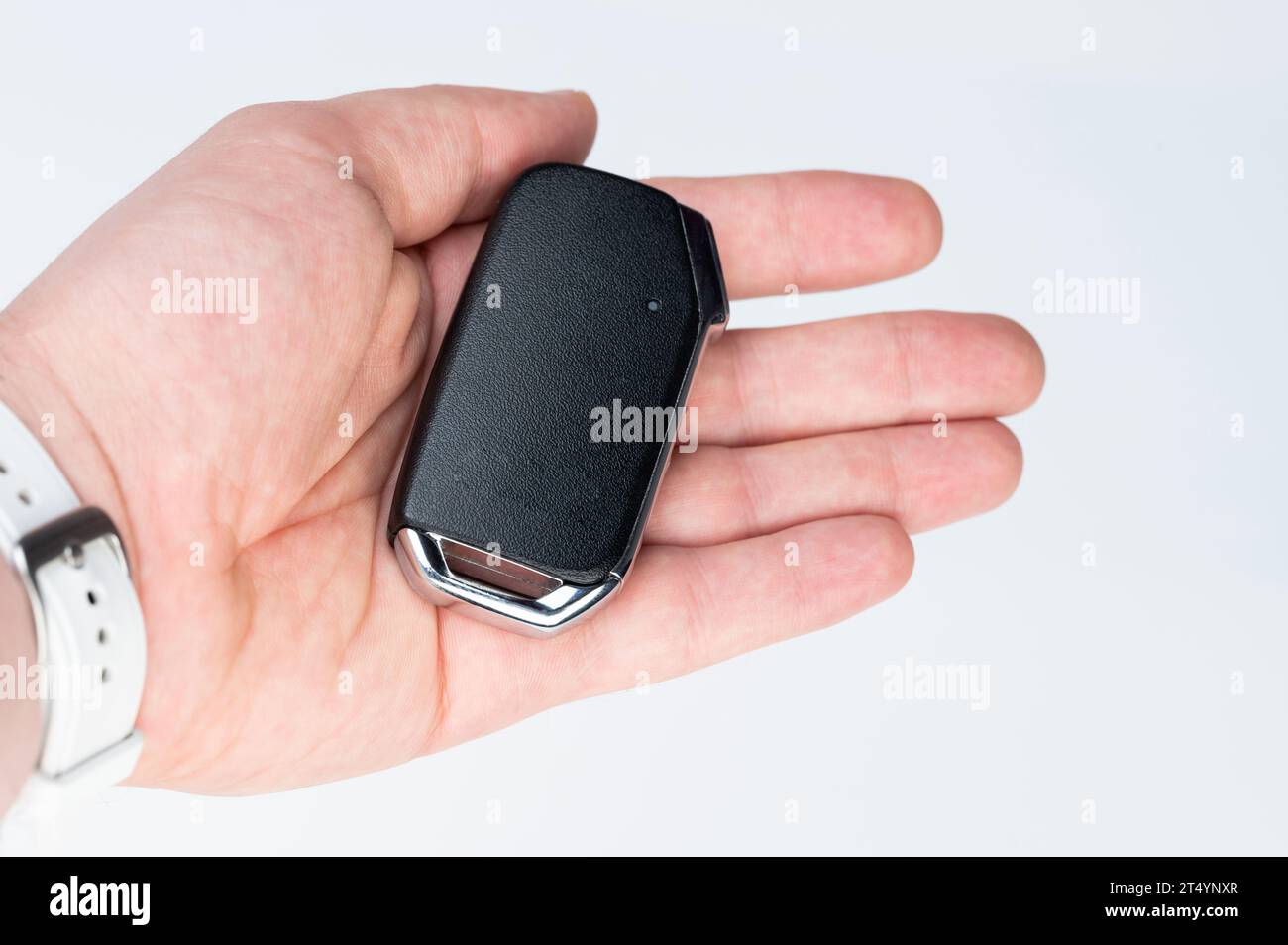 Modern car key in hand isolated on white studio background Stock Photo