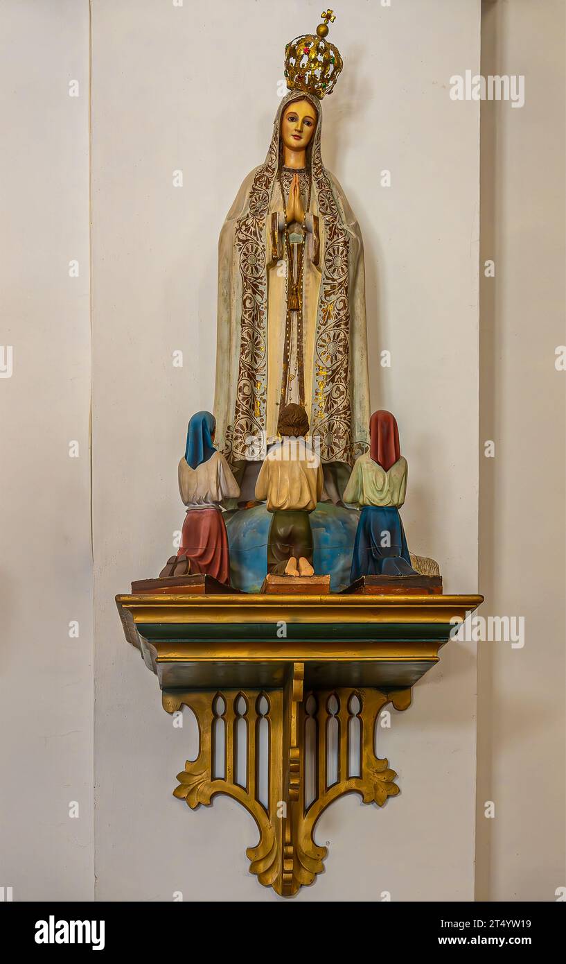 Guatemala, La Antigua - July 20, 2023: San Jose Cathedral.  Statue of Virgin Mary at her apparition in Fatima before 3 children. Beige wall in back. G Stock Photo