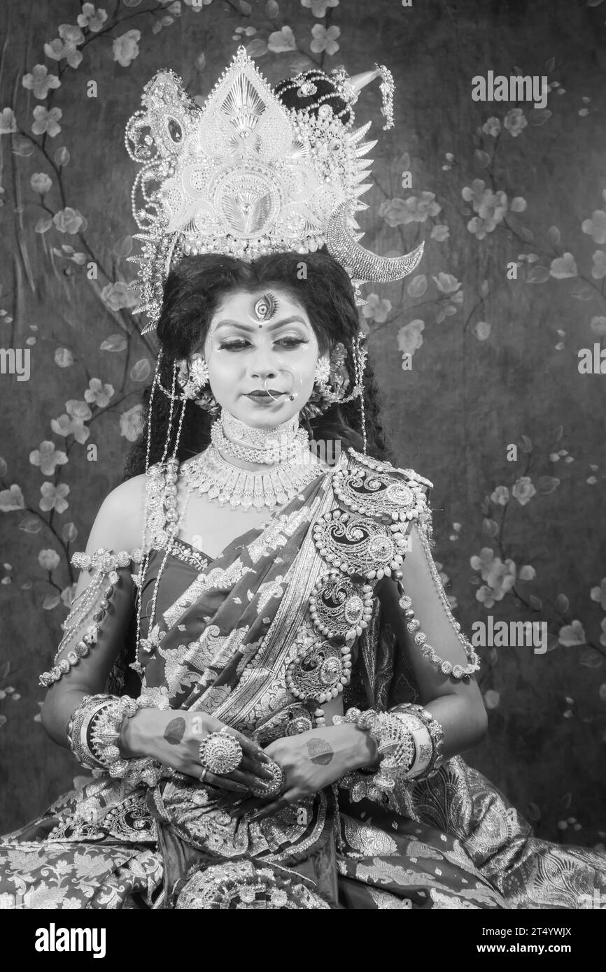 Portrait of beautiful Indian girl of Durga Idol Agomoni Concept Indoor Photo wearing traditional Indian saree, gold jewellery, and bangles. Maa Durga. Stock Photo