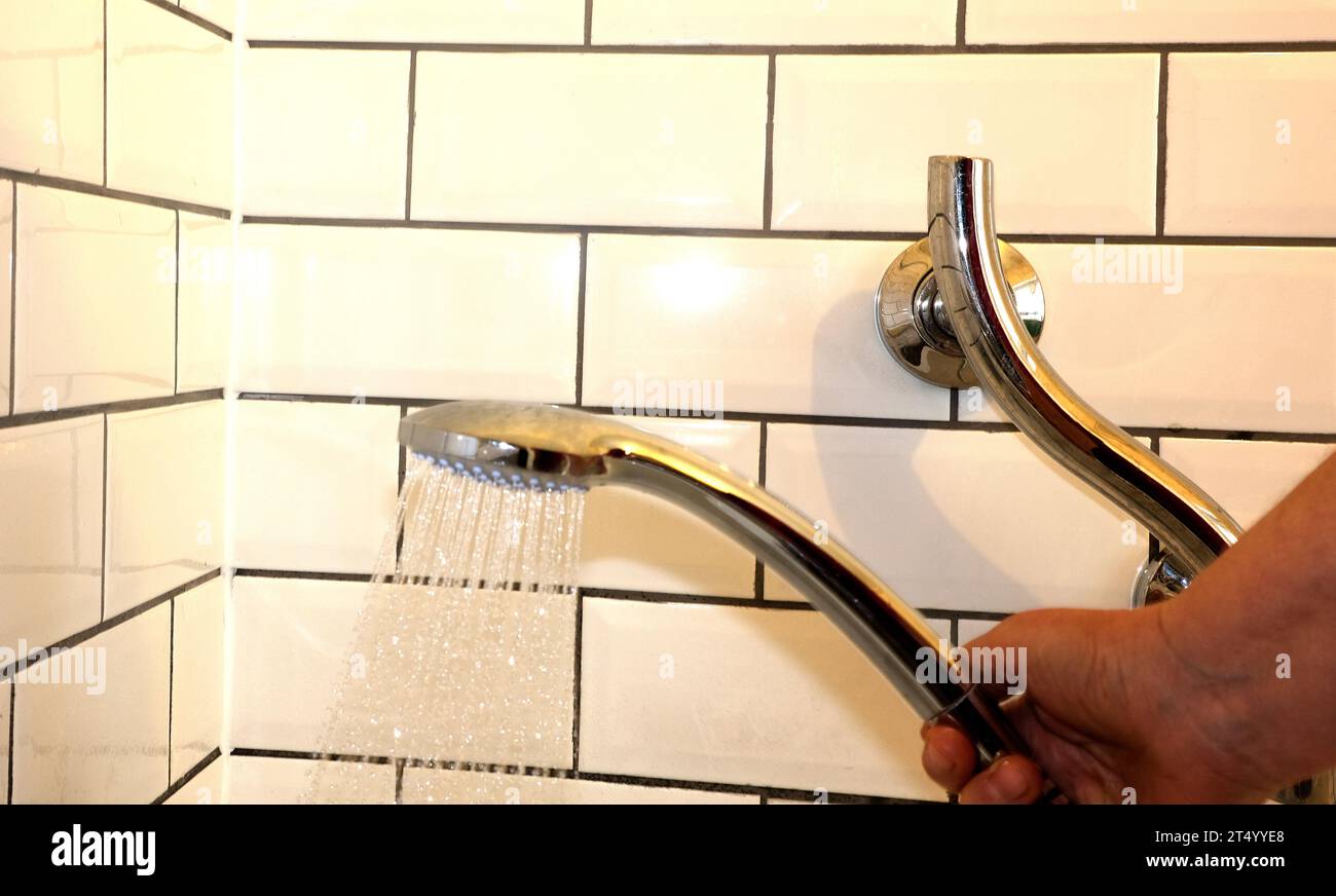 gripped hand holding showerhead with running water Stock Photo Alamy