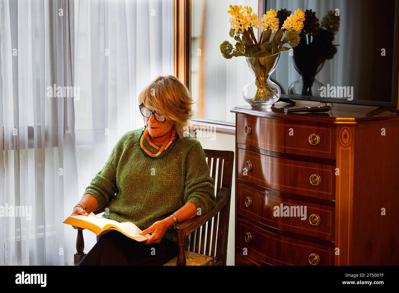 Relaxed older woman sitting in bedroom reading Stock Photo
