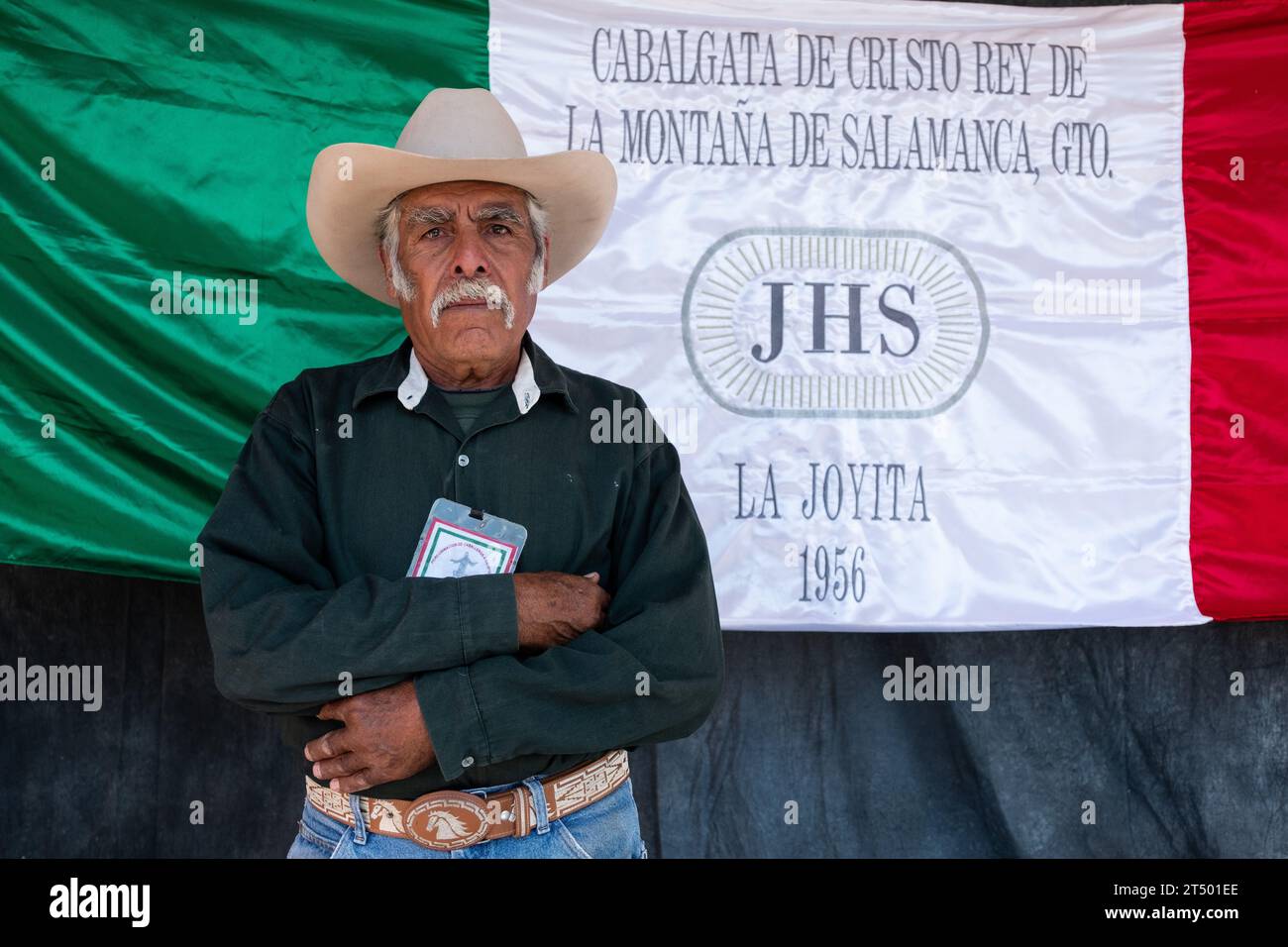 An elderly Mexican cowboy from La Joyita, Chihuahua state, poses by his groups banner during the annual Cabalgata de Cristo Rey pilgrimage, January 5, 2019 in Salamanca, Guanajuato, Mexico. Thousands of Mexican cowboys and horse take part in the three-day ride to the mountaintop shrine of Cristo Rey. Stock Photo