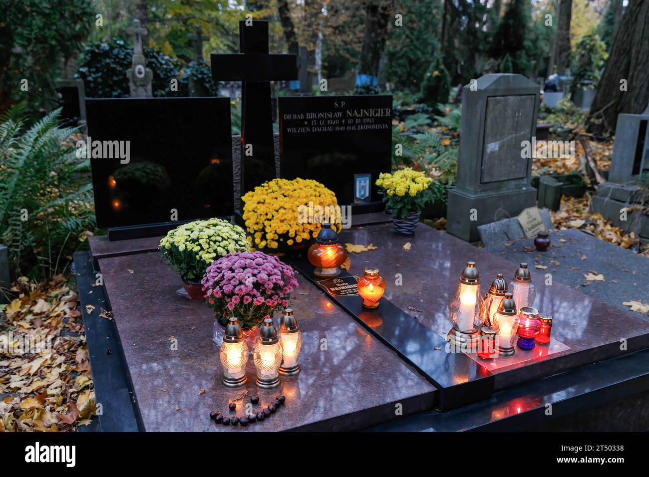 Candles are placed on the grave without name on All Saints' Day at the Evangelical-Augsburg Cemetery in Warsaw. All Saints' Day (or Dzie? Zaduszny in Polish) is a public holiday in Poland. It is an opportunity to remember deceased relatives. On this day, people bring flowers, typically chrysanthemums, and candles to cemeteries. The entire cemetery is filled with lights in the darkness. The Evangelical-Augsburg Cemetery is a historic Lutheran Protestant cemetery located in the western part of Warsaw. Since its opening in 1792, more than 100,000 people have been buried there. (Photo by Volha Shu Stock Photo