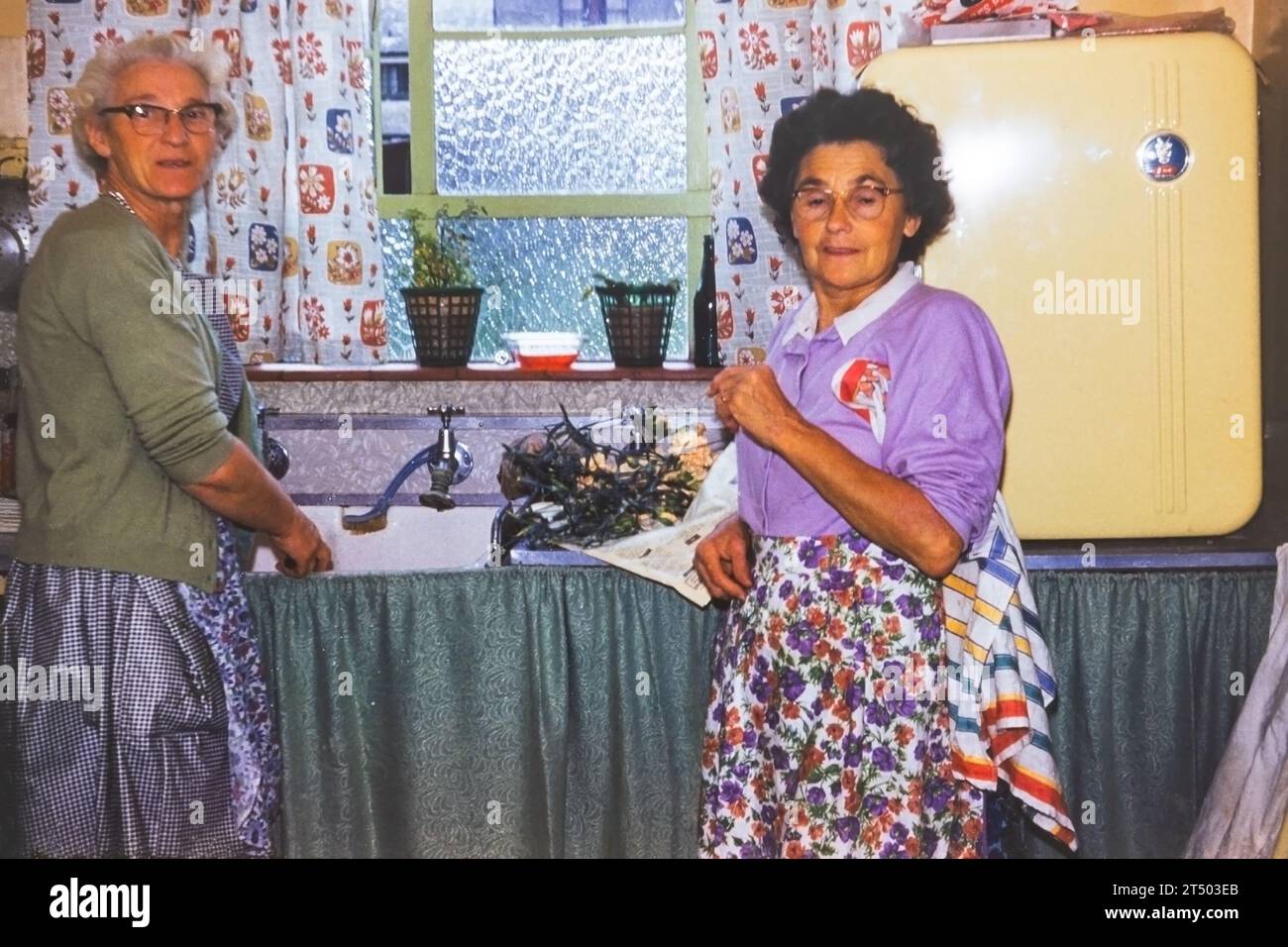 2 older Scottish women at the kitchen sink of a council house in the 1960's. Transparency film scan. Stock Photo