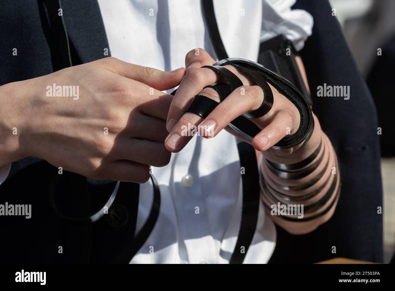 A Jewish man wraps the black leather straps of his tefillin around his