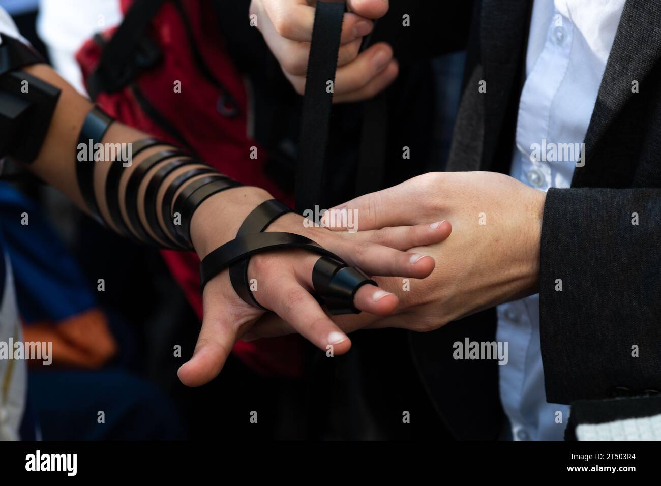 A Jewish man wraps the black leather straps of his tefillin around his