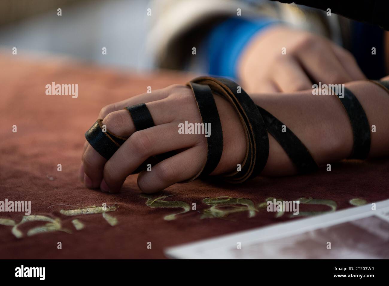 A Jewish man wraps the black leather straps of his tefillin around his