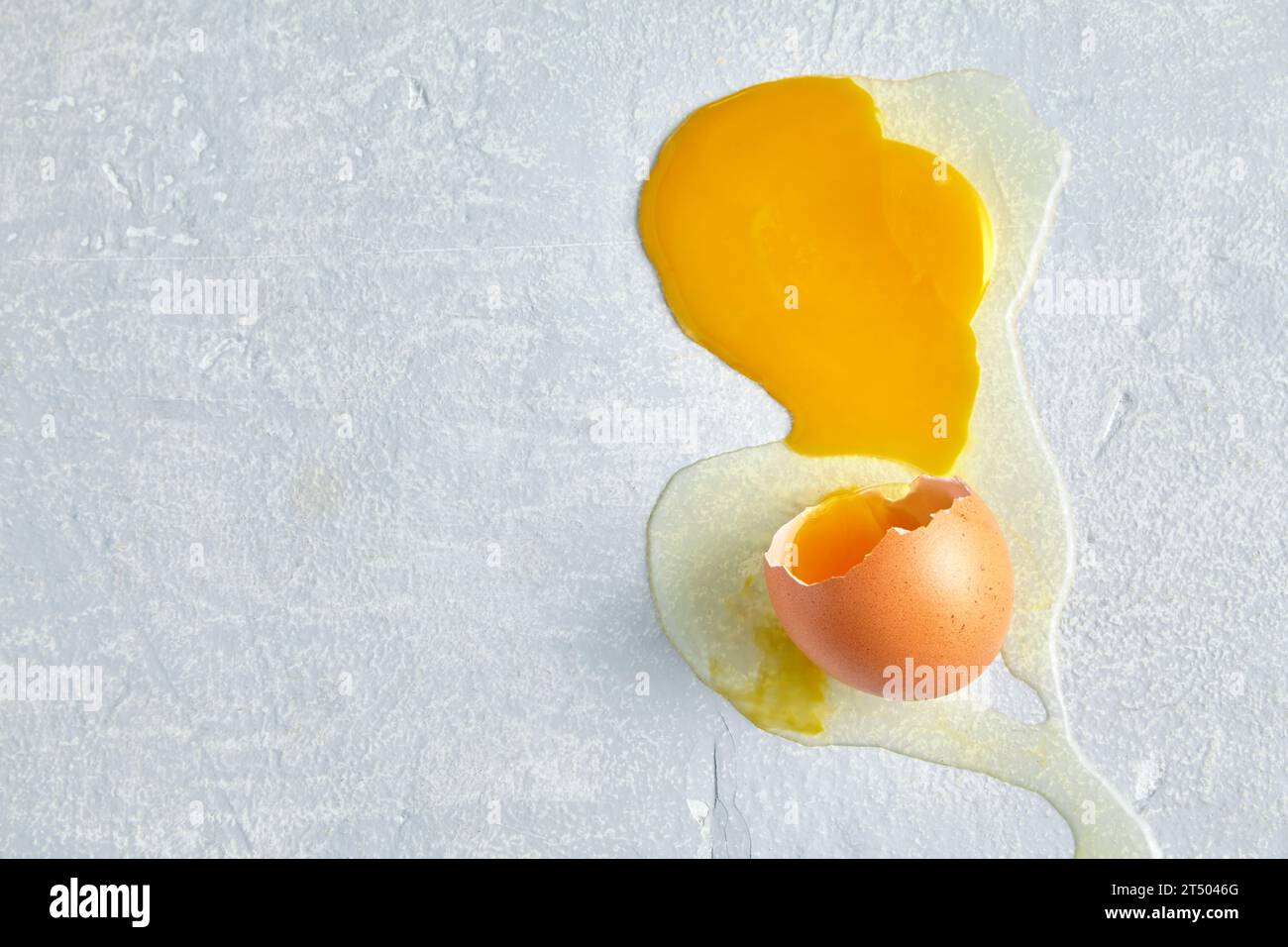 Broken and spread egg on a gray concrete floor Stock Photo