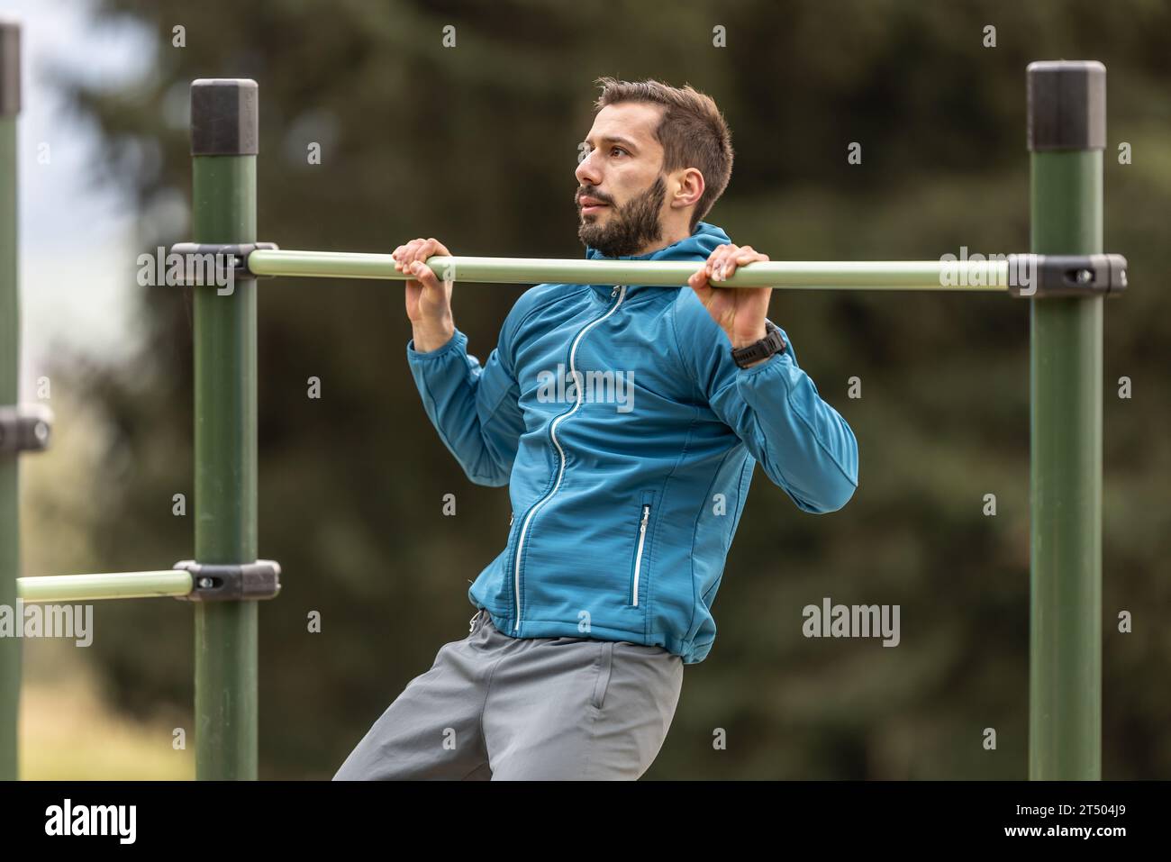 Young man working out calisthenics in an outdoor gym using parallel