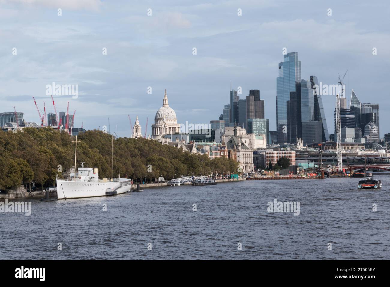 A view of the River Thames, H.M.S. Wellington and the skyscrapers of the City of London skyline, as seen from Waterloo Bridge, London, England, UK Stock Photo