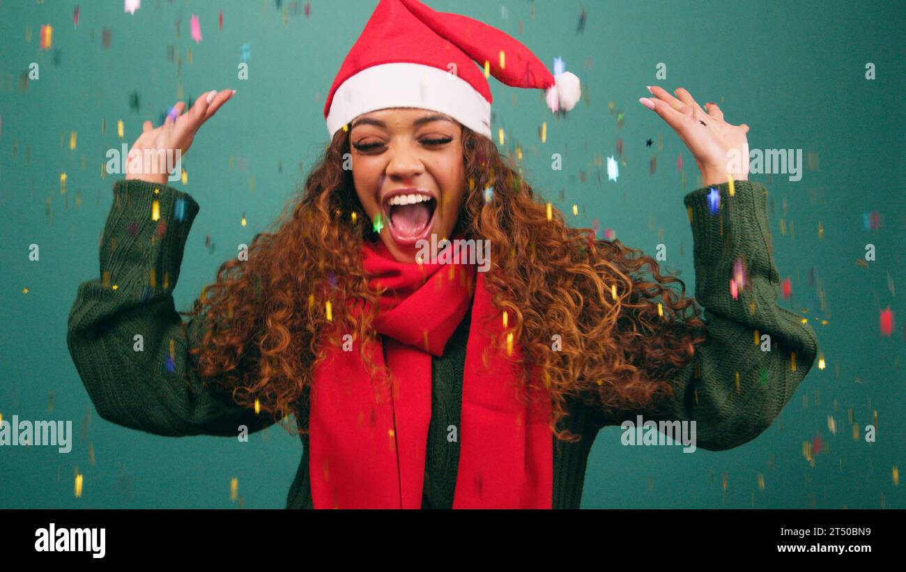 Happy young woman tosses rainbow confetti and dances at Christmas, studio Stock Photo