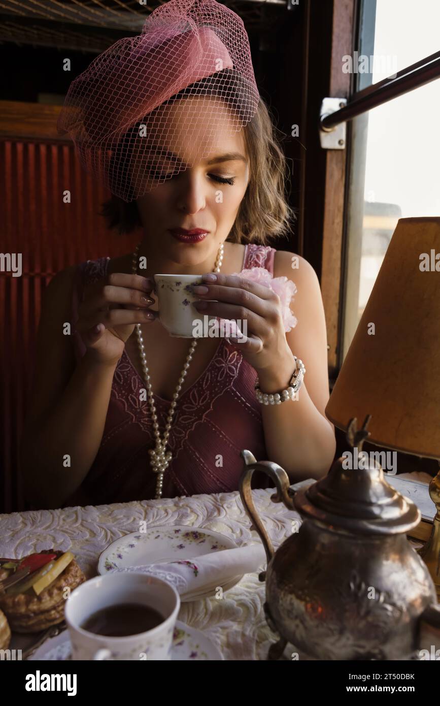 Reenactment scene of a 1920s flapper dress lady enjoying high tea in an