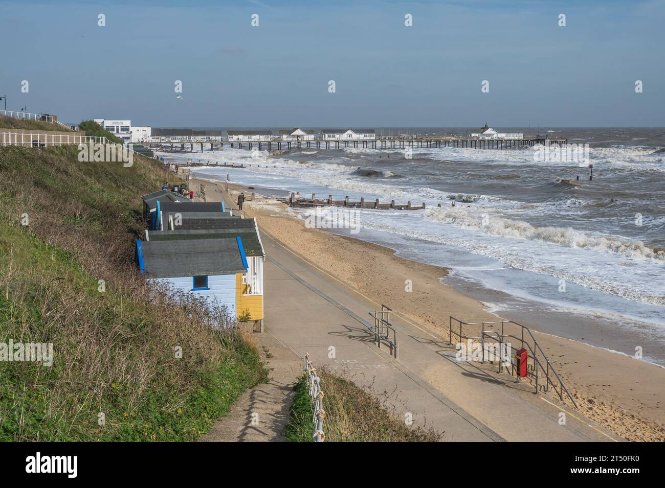 The image of Southwold promenade with its colourful beach huts looking towards Southwold Pier at the coastal resort town of Southwold in Suffolk Stock Photo