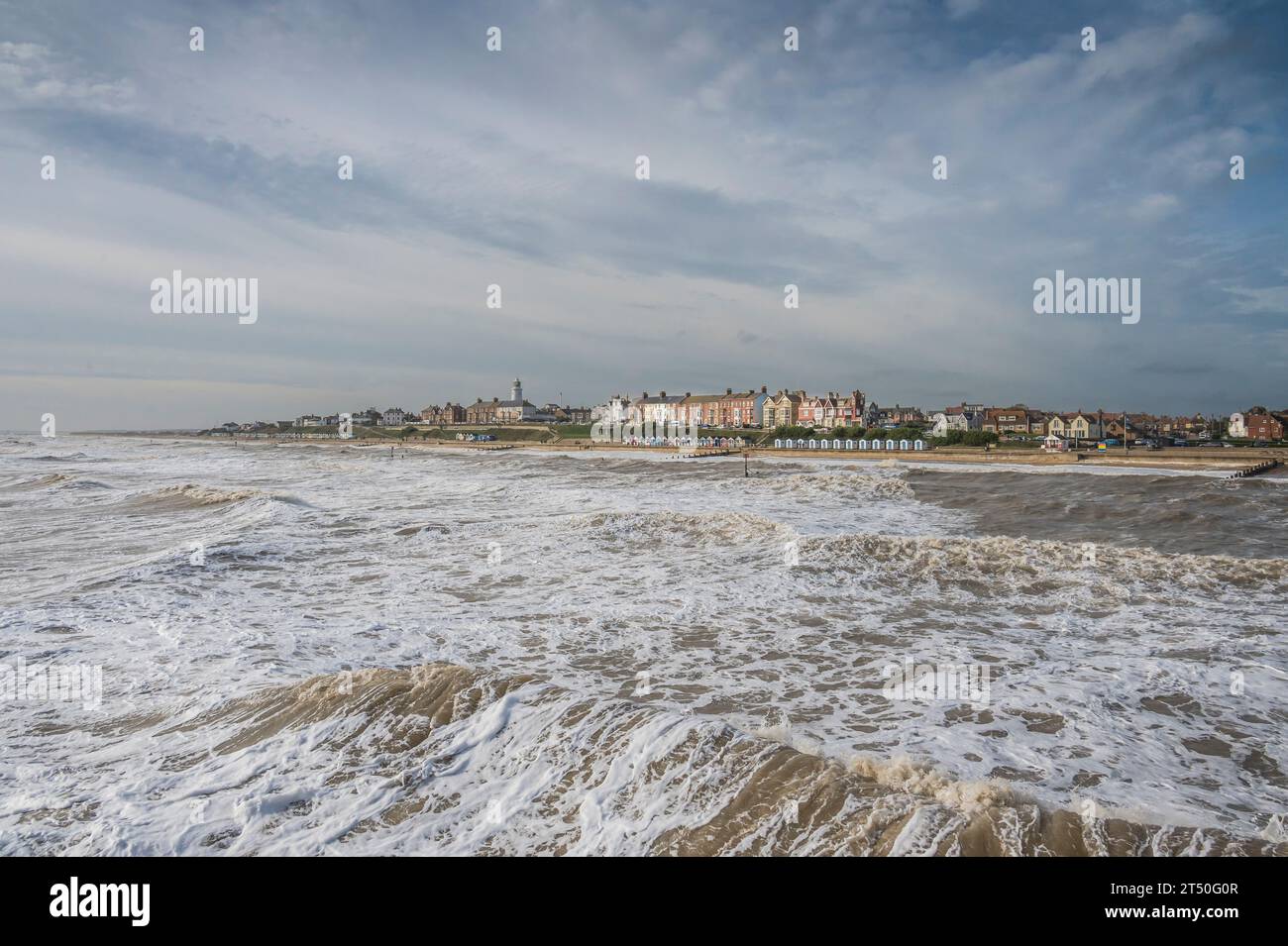 The image from Southwold Pier looking towards the lighthouse and promenade beach huts is at the coastal resort town of Southwold in Suffolk Stock Photo