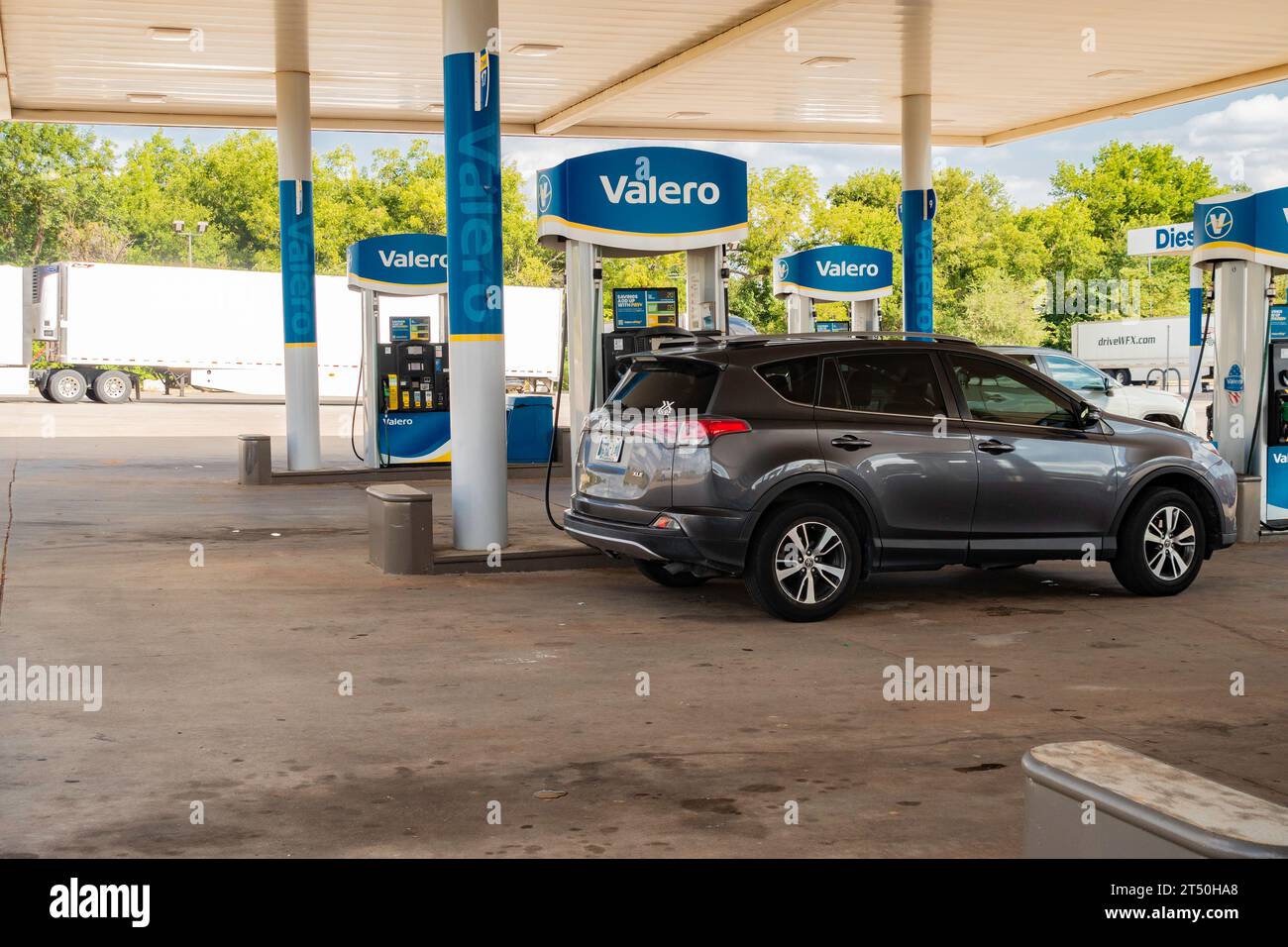 An automobile parked next to Valero brand gasoline or petrol pumps at a filling station or refueling station in Guthrie, Oklahoma, USA. Stock Photo