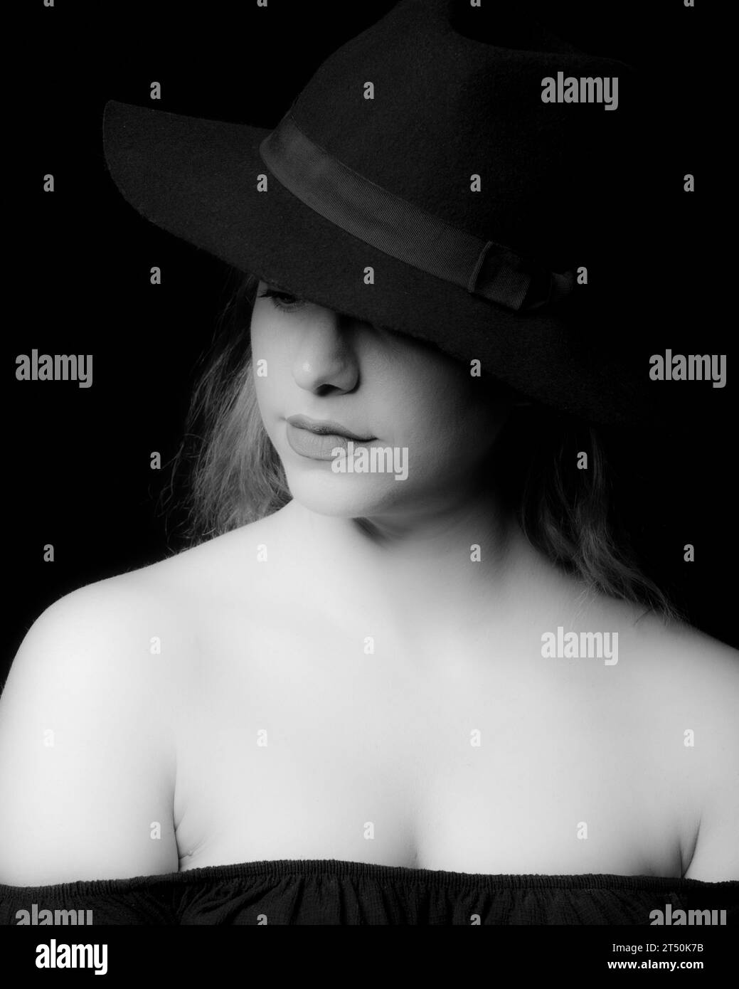 High contrast black and white portrait of an attractive woman wearing black hat Stock Photo