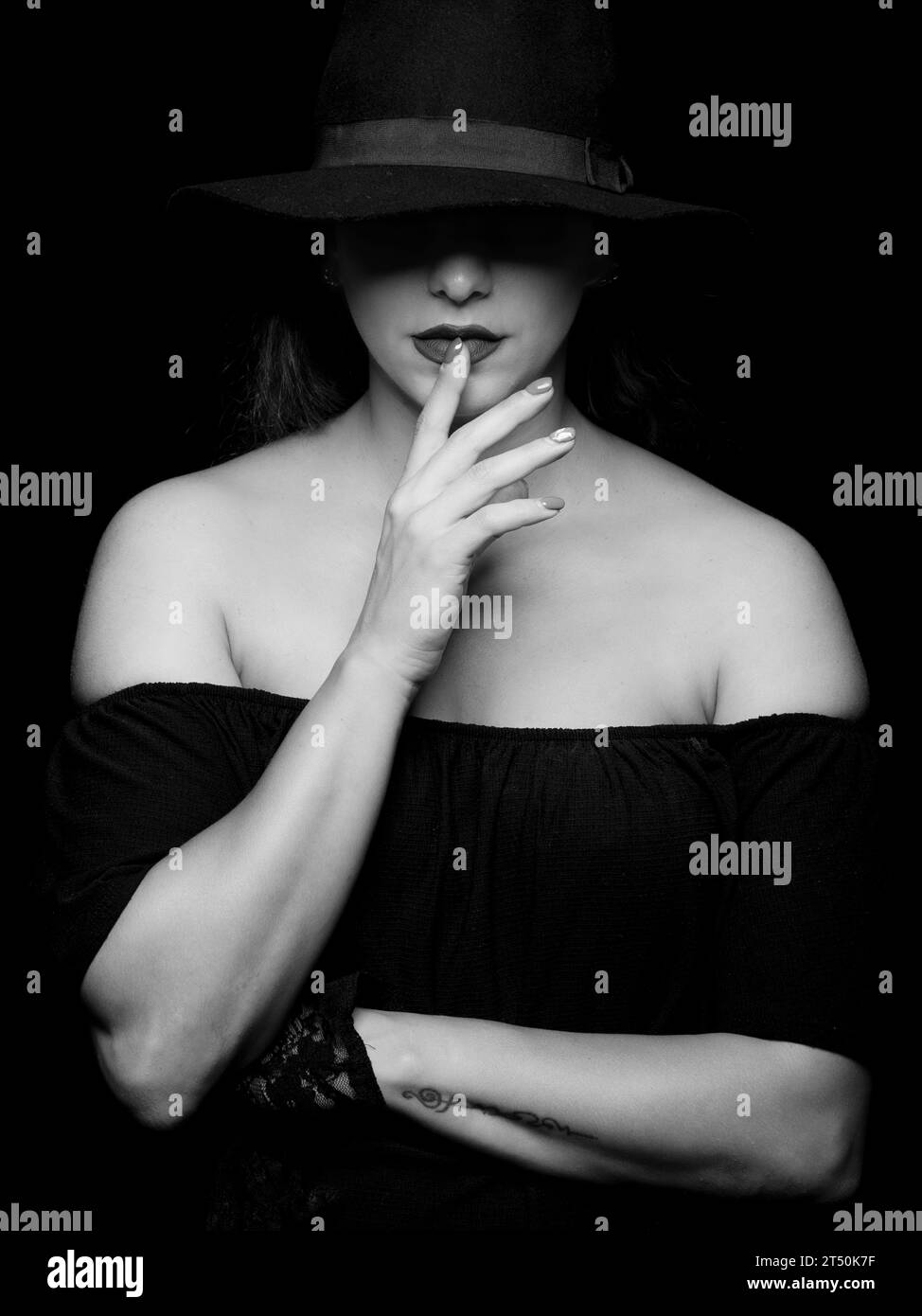 Portrait of a young caucasian woman wearing hat with hand on lips. Stock Photo