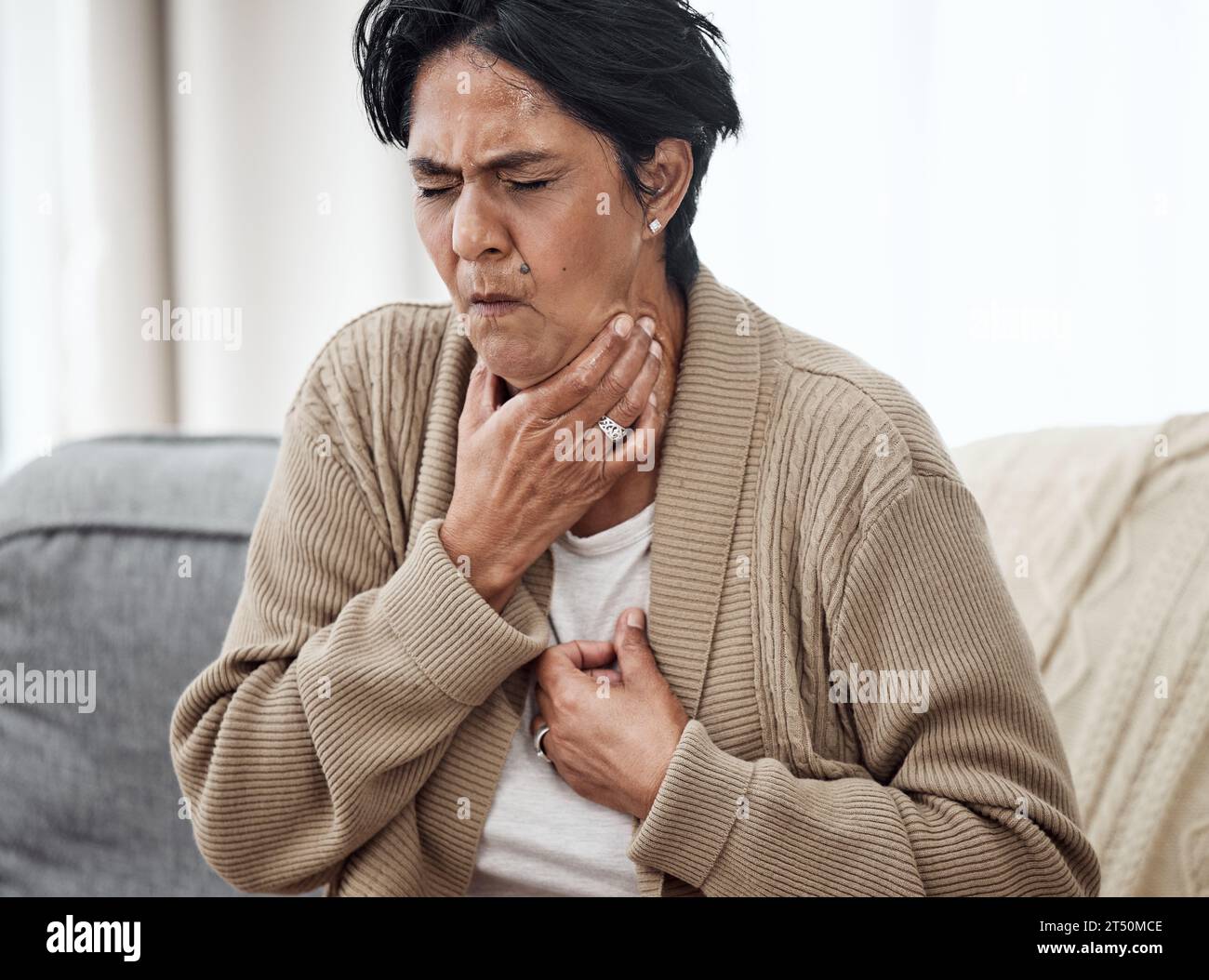 Senior woman, cough and sick on sofa in home, chest pain and pneumonia