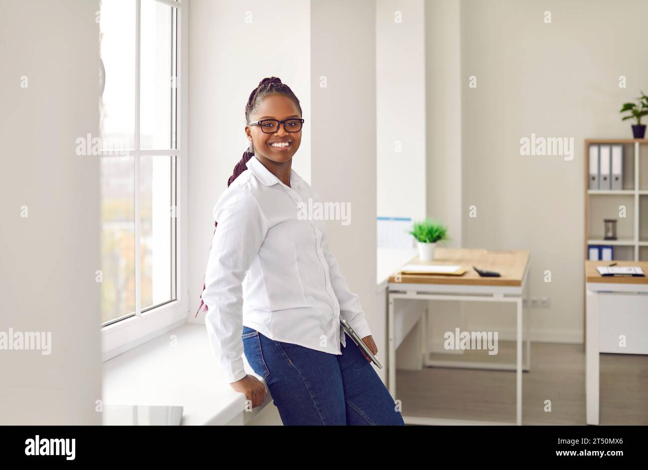Cheerful young woman standing and looking at camera Stock Photo