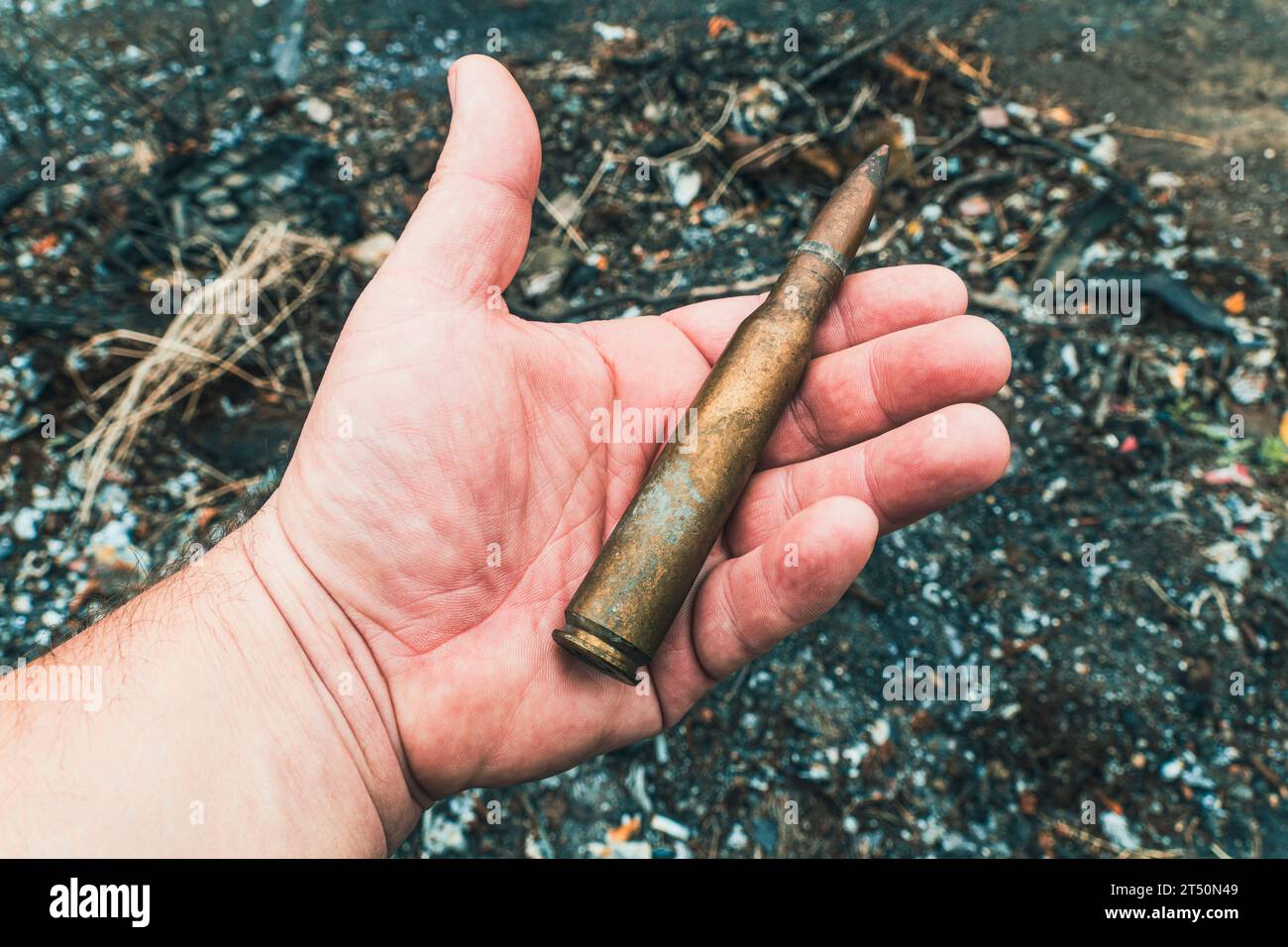 A largecaliber machine gun cartridge in a hand against the backdrop of
