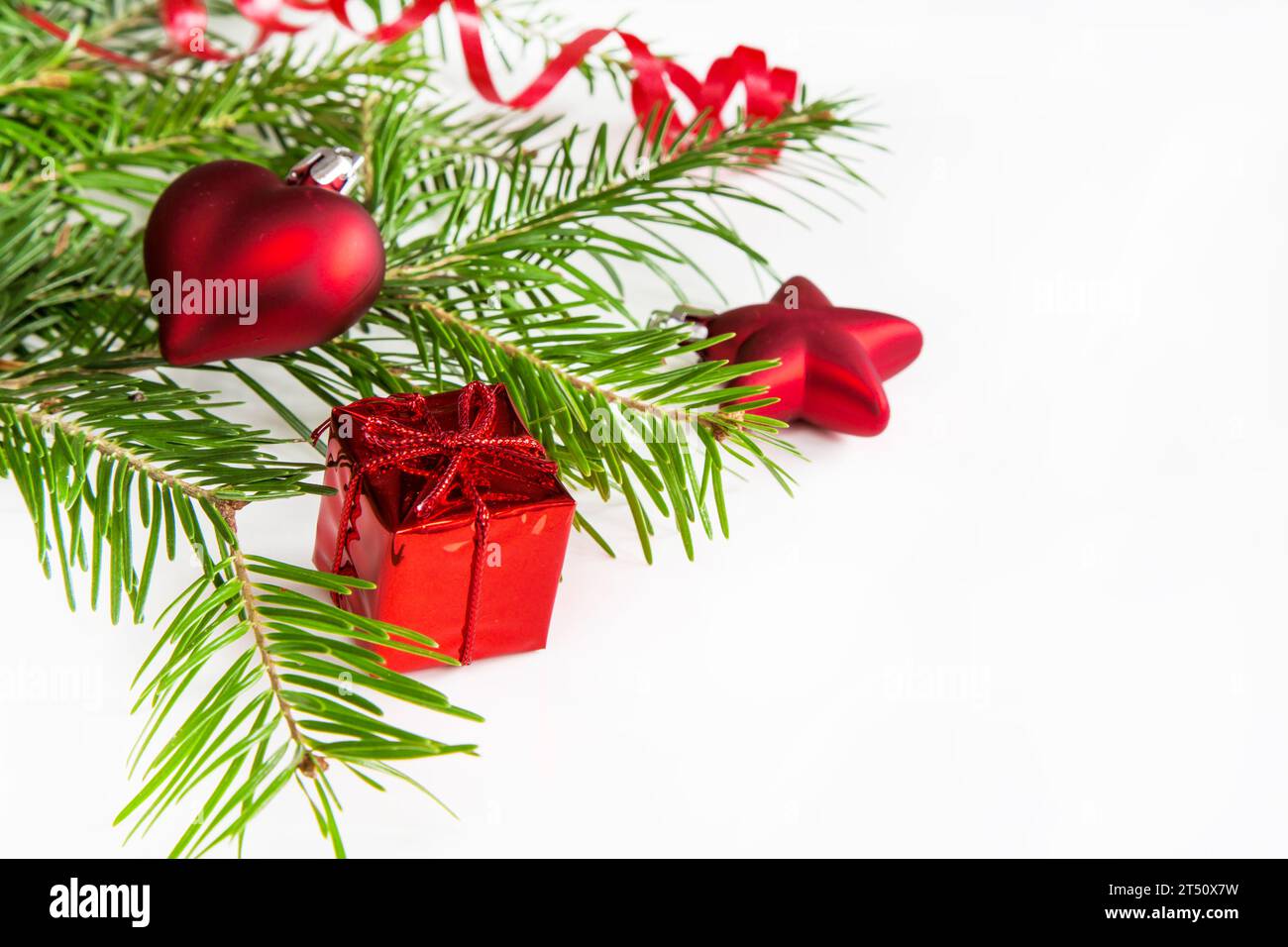 Closeup of pine branch, red colored Christmas decoration box, heart, star on white background with copy space Stock Photo