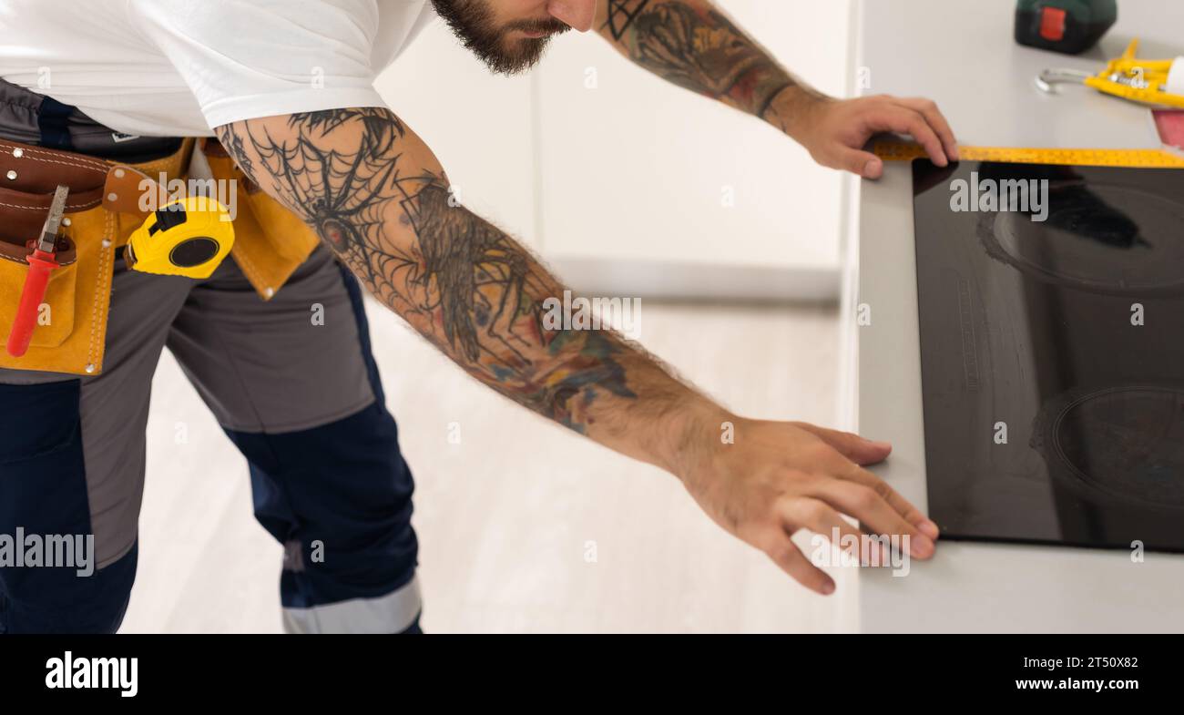 man sets hob in kitchen. Installation an induction hob above oven. Work