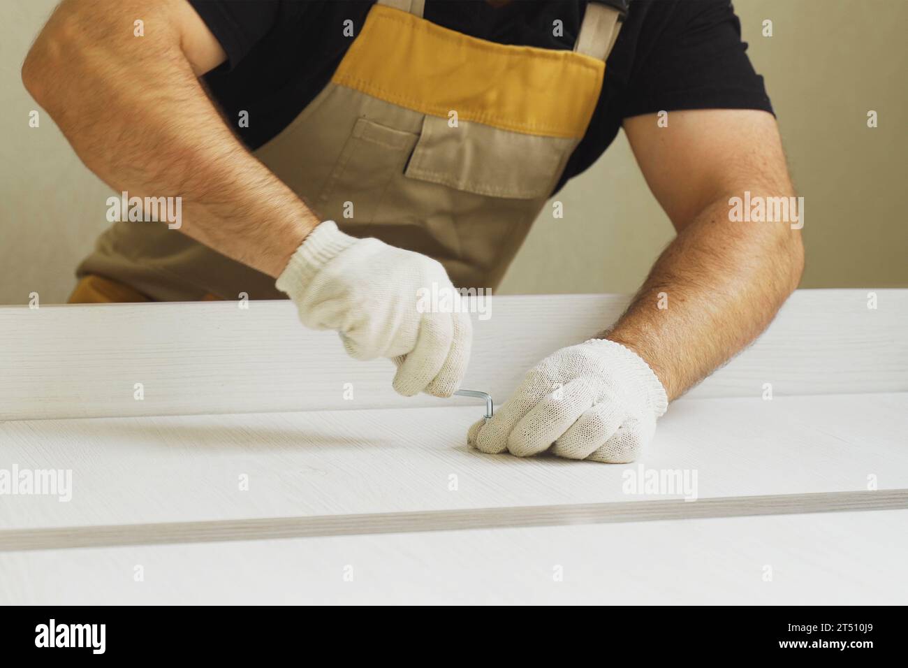 Furniture assembly. A worker fastens the parts of a bed using confirmat ...