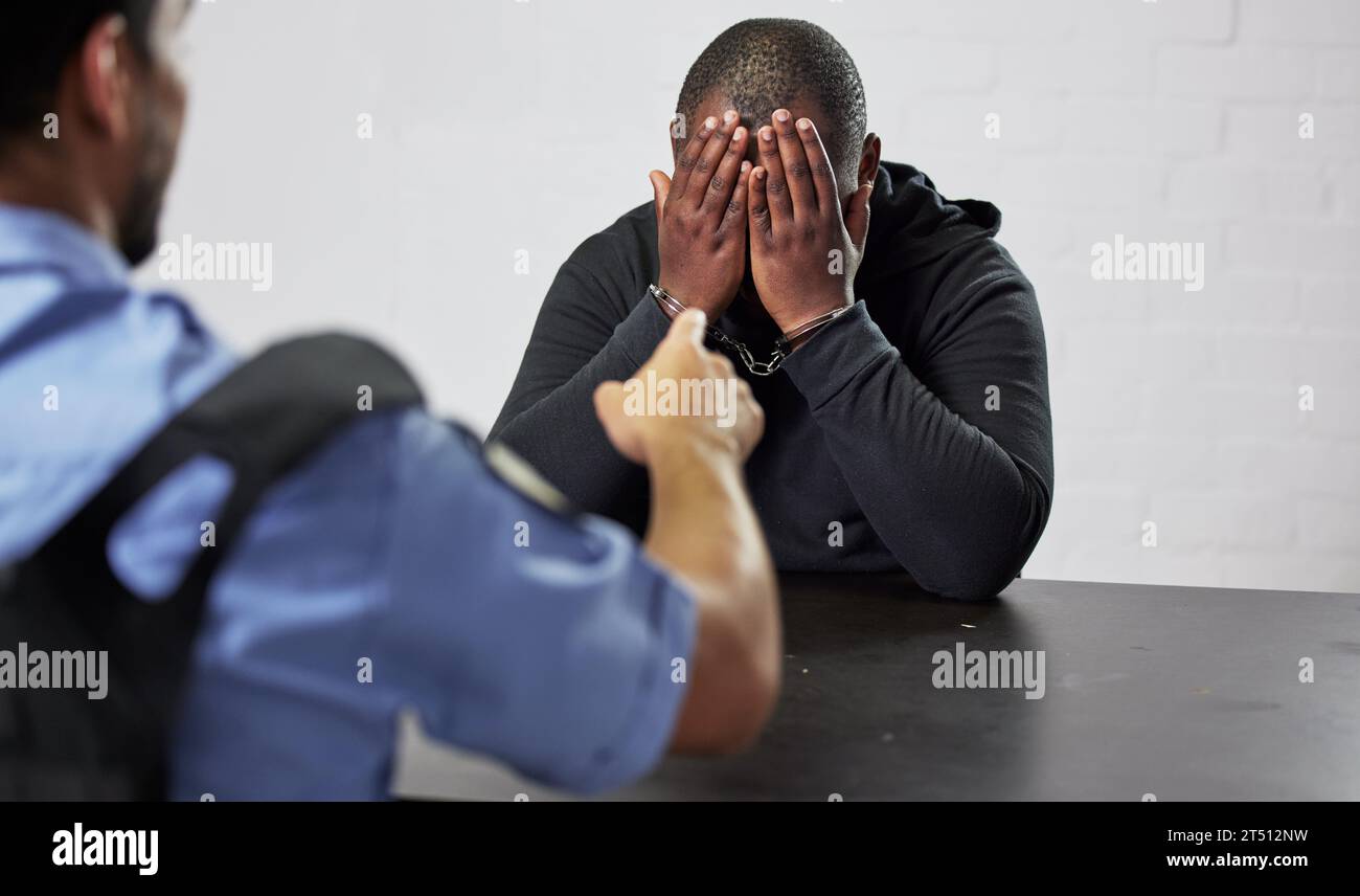 Policeman, criminal and handcuffs for interrogation, question or arrest in fraud, scam or crime. Law enforcement officer pointing to prisoner Stock Photo
