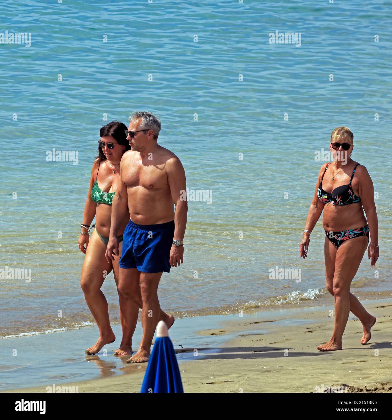Three people enjoying Playa Dorada beach, Lanzarote. Taken March 2023 Stock Photo