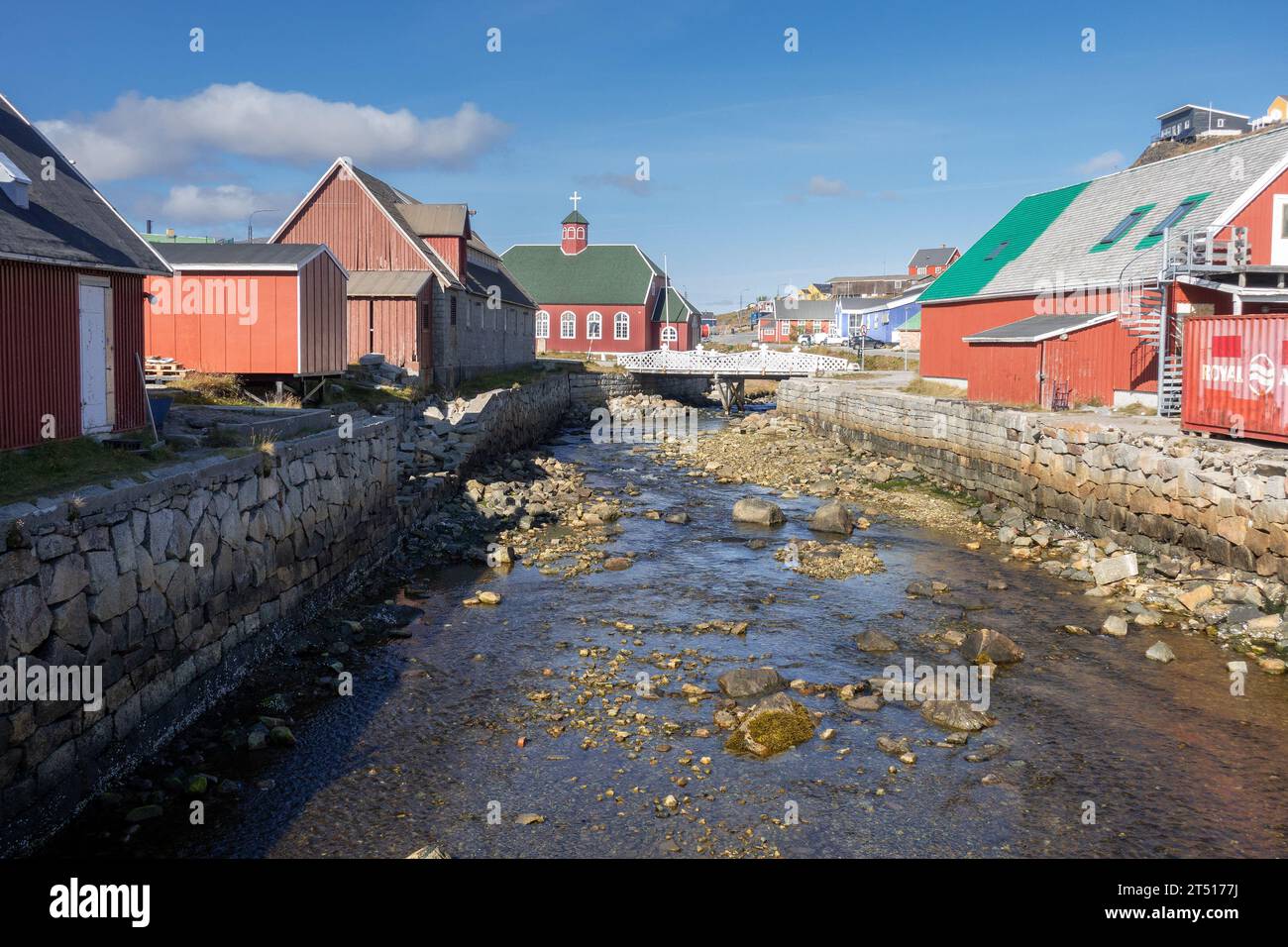 Small River Stream Running Through The Middle Of Qaqortoq Town In Greenland, The Church of Our Savior In The Background Stock Photo