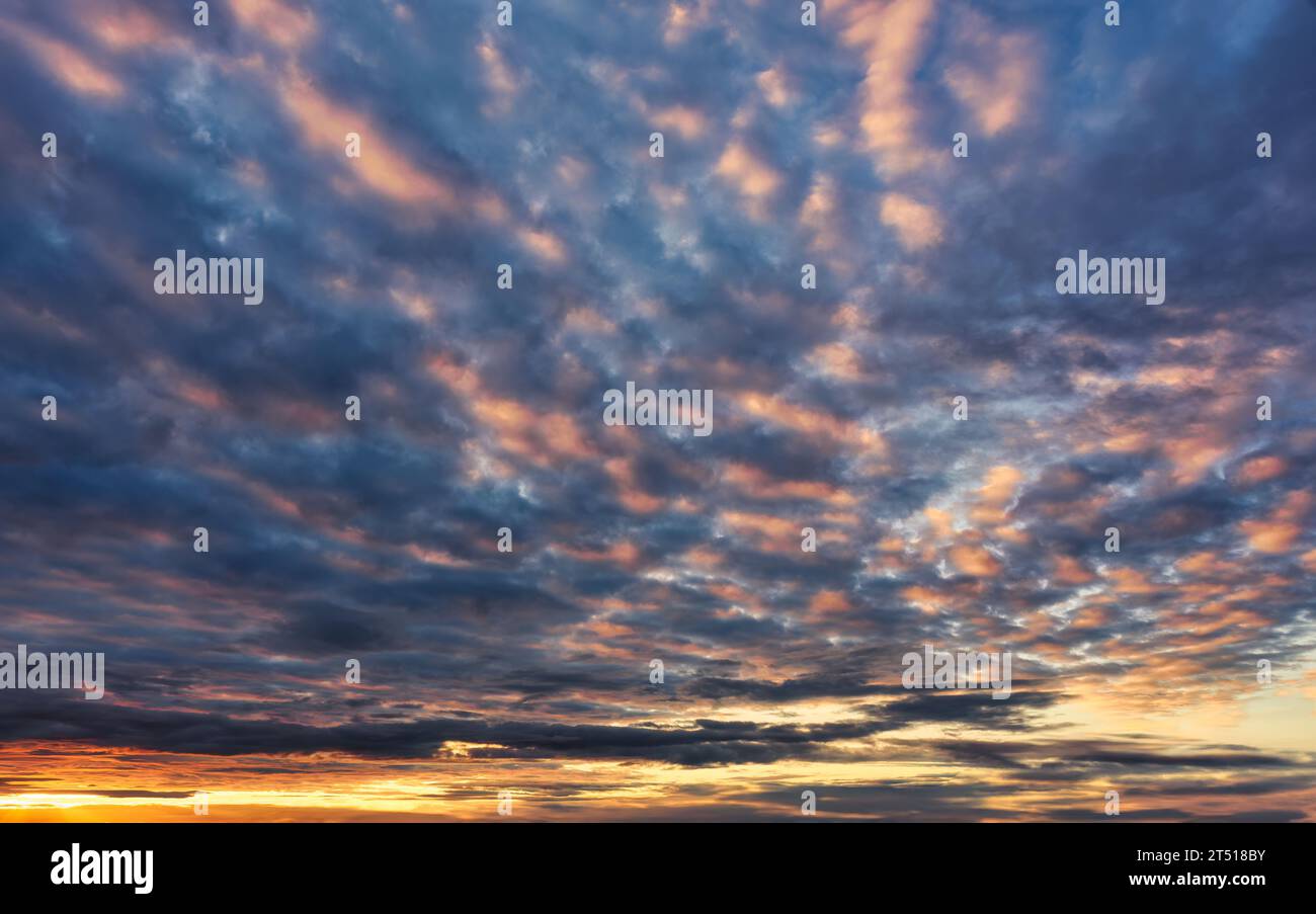 Beautiful vibrant fluffy clouds in sunset sky at twilight Stock Photo