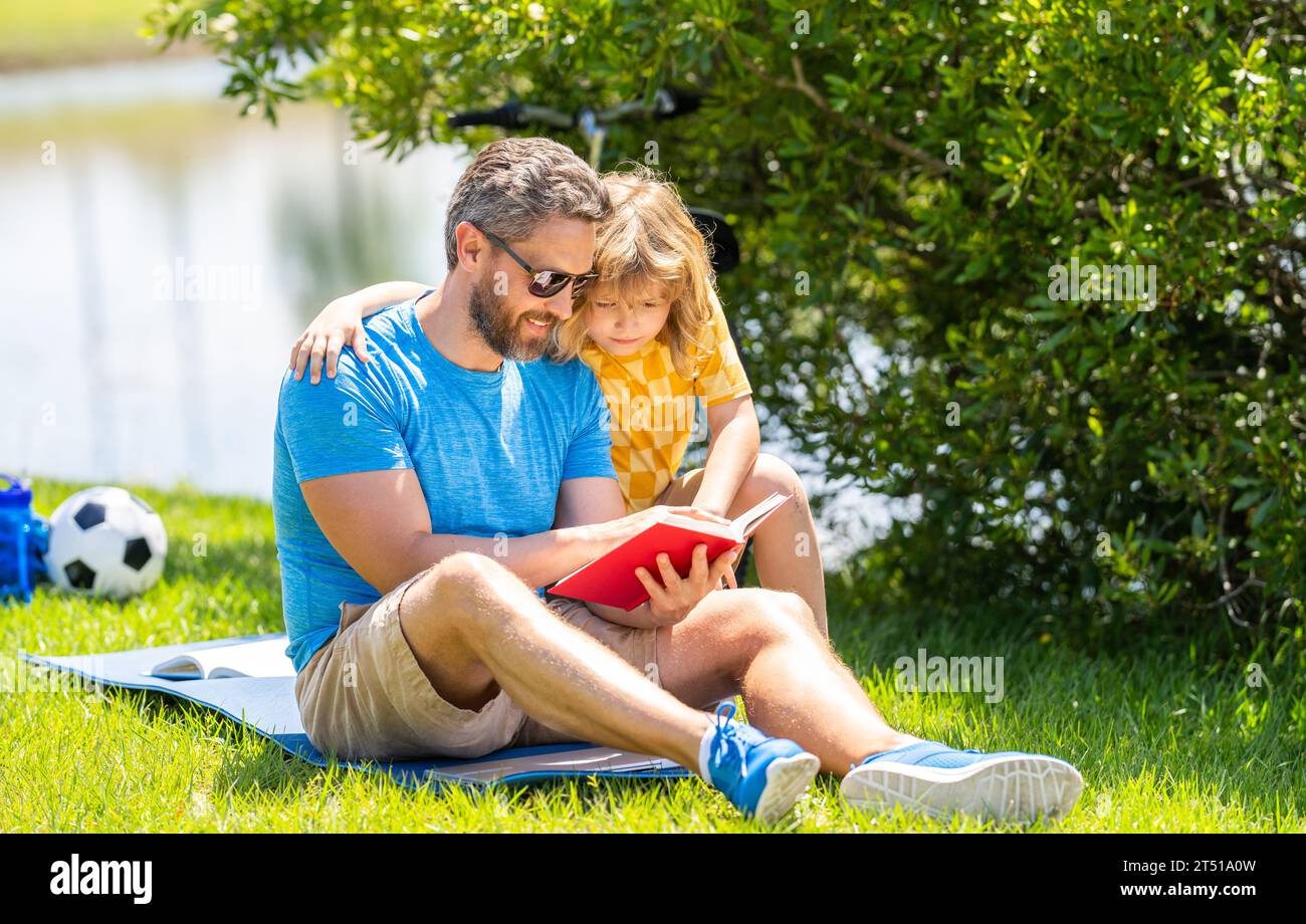 dad and kid reading book. dad and son read outdoor. dad and son create literary adventures in nature. dad son outdoor reading time. cherished traditio Stock Photo