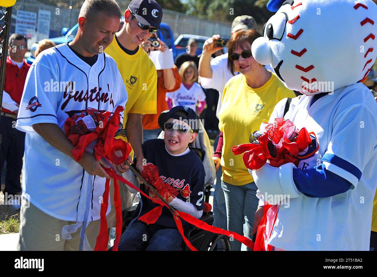 110722-N-YR391-024 CAMDEN COUNTY, Ga. (Oct. 22, 2011) Senior Chief Missile Technician Jeff Norris and the Miracle League mascot hold a ribbon for a child to cut and officially open the newly constructed Miracle Field in Camden County, Ga. Miracle Field is a specialized baseball field that will serve children with disabilities in Camden County and the surrounding areas. (U.S. Navy photo by Mass Communication Specialist 2nd Class Gary Granger Jr./Released) Stock Photo