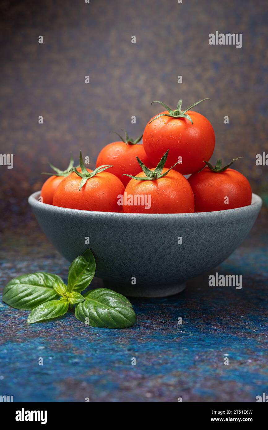 Tomatoes in a white bowls with a basil leave Stock Photo - Alamy