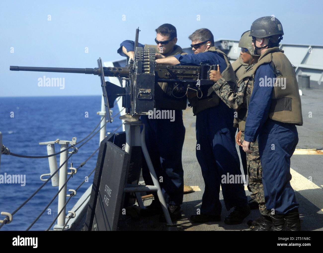 0905254879G-491 ATLANTIC OCEAN (May 25, 2009) A Honduran Infanteria De Marine waits as U.S. Navy Sailors clear a jam in a .50 caliber machine gun during a multi-national gunnery exercise aboard the guided-missile frigate USS Doyle (FFG 39). The Honduran marines were aboard Doyle for a Southern Seas 2009 multi-national damage control and weapons training exercise. Navy Stock Photo