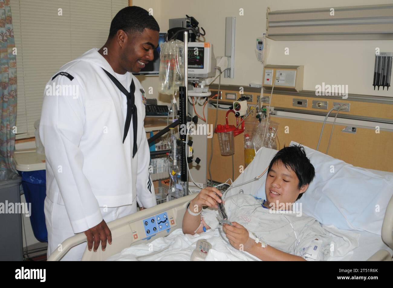 1006047783B-001 PORTLAND, Ore. (June 4, 2010) Ship's Serviceman 1st Class Michael Davis, left, assigned to the guided-missile destroyer USS Sampson (DDG 102), talks to a patient at Doernbecher Children's Hospital during a hospital visit. Sampson is conducting a port visit to Portland during the 2010 Portland Rose Festival. Navy Stock Photo