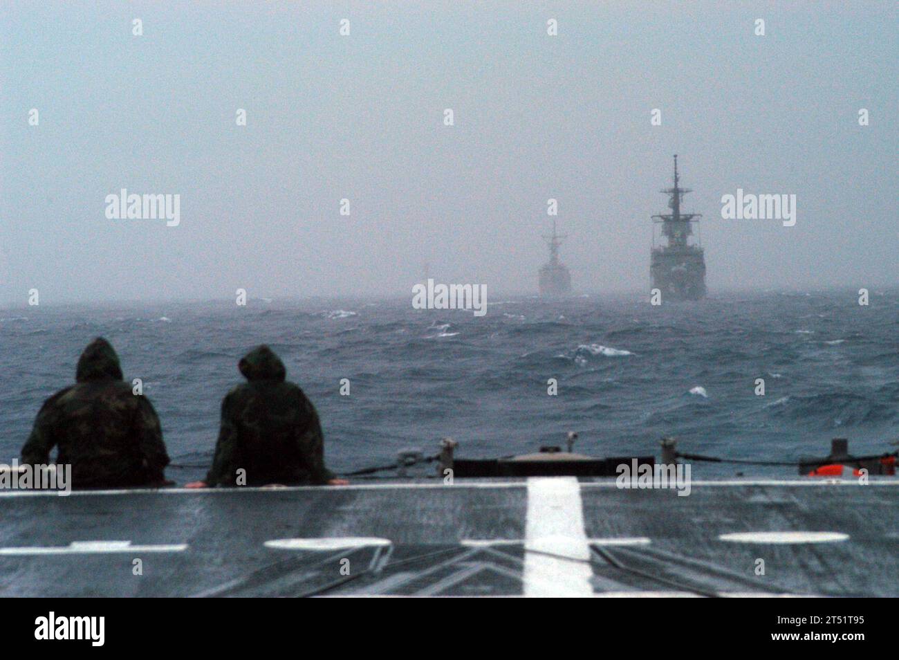 0806133581D-006 GULF OF THAILAND (June 13, 2008) Two Sailors watch the Royal Thai Navy frigate HTMS Phutta Loetla Naphalai (FF 462) and the frigate USS Ford (FFG 54) encounter rough seas, low visibility, high winds, and rain squalls from the fantail of the frigate USS Jarrett (FFG 33). Jarrrett is one of several U.S. and Thai ships taking part in Cooperation Afloat Readiness and Training (CARAT) 2008. U.S. Navy Stock Photo