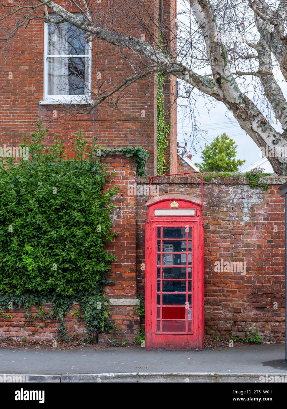 A Red British/English Telephone box in a village setting. Stock Photo
