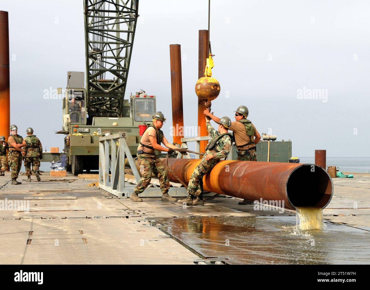 0807311424C-336 CAMP PENDLETON, Calif. (July 31, 2008) Seabees assigned to Amphibious Construction Battalion (ACB) 1 and Amphibious Construction Battalion (ACB) 2 unhook crane cables from the pile as ocean water flows out onto the deck of the elevated causeway system (ELCAS) as the ELCAS pier deconstruction continues during Joint Logistics Over-The-Shore 2008. Navy Stock Photo
